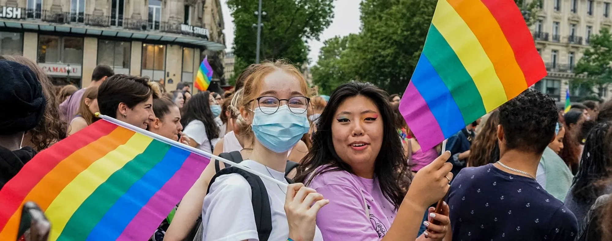 Students holding rainbow pride flags during a community event promoting inclusion and belonging