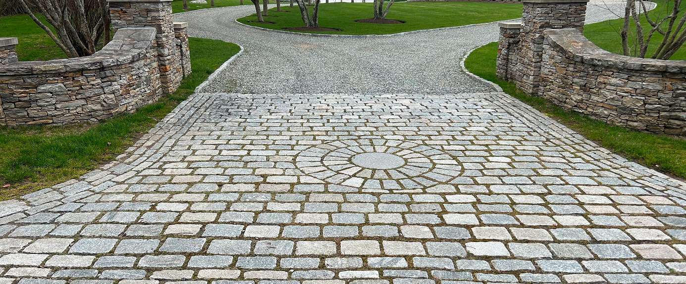 Stone pathway with a circular pattern in the center, bordered by stone walls and green grass.