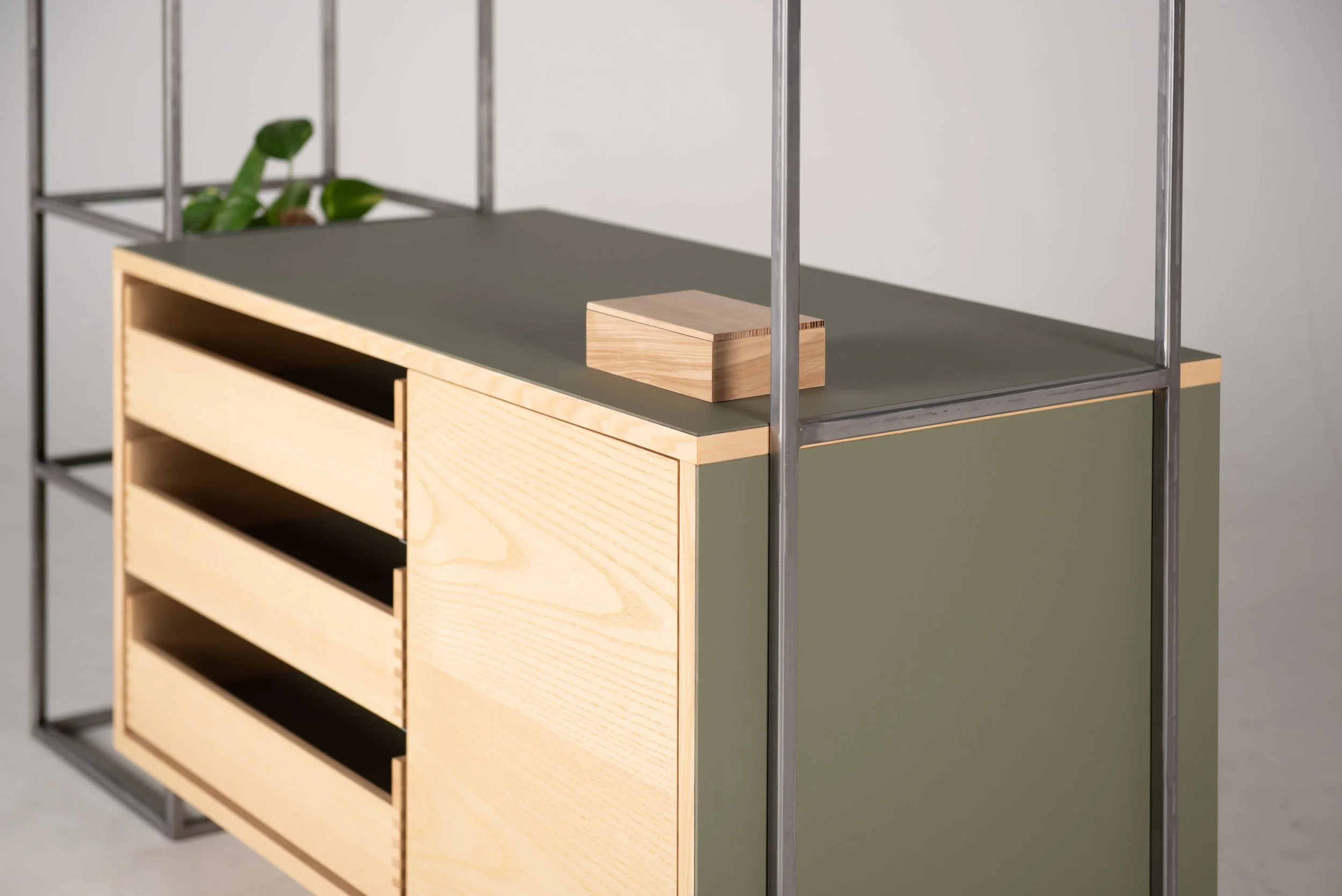 Ein moderner Schrank mit Holz- und grauen Elementen, daneben ein metallener Regalrahmen.