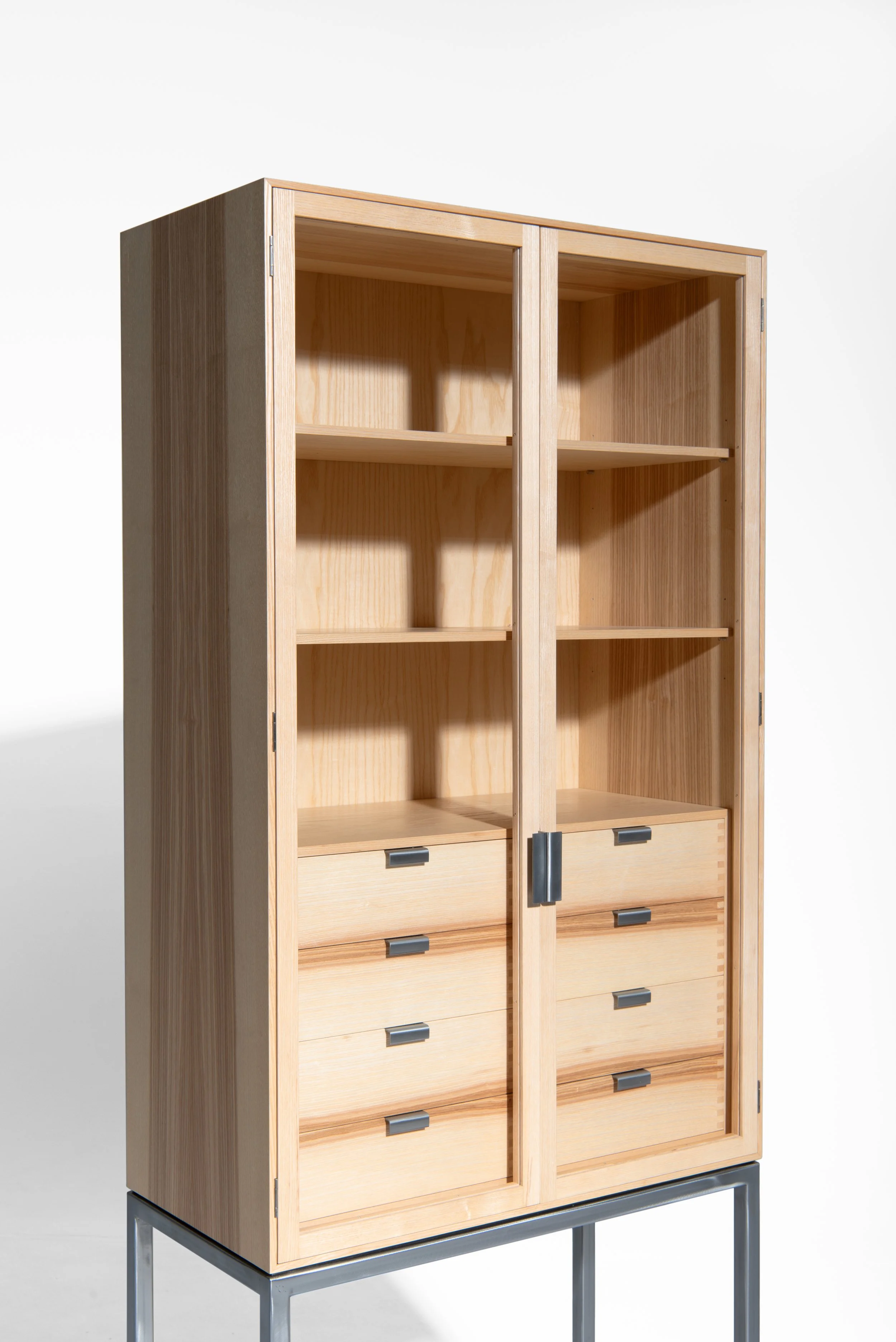 Ein Holzkabinett mit Glastüren, vier Schubladen und schwarzem Metallgestell auf weißem Hintergrund.