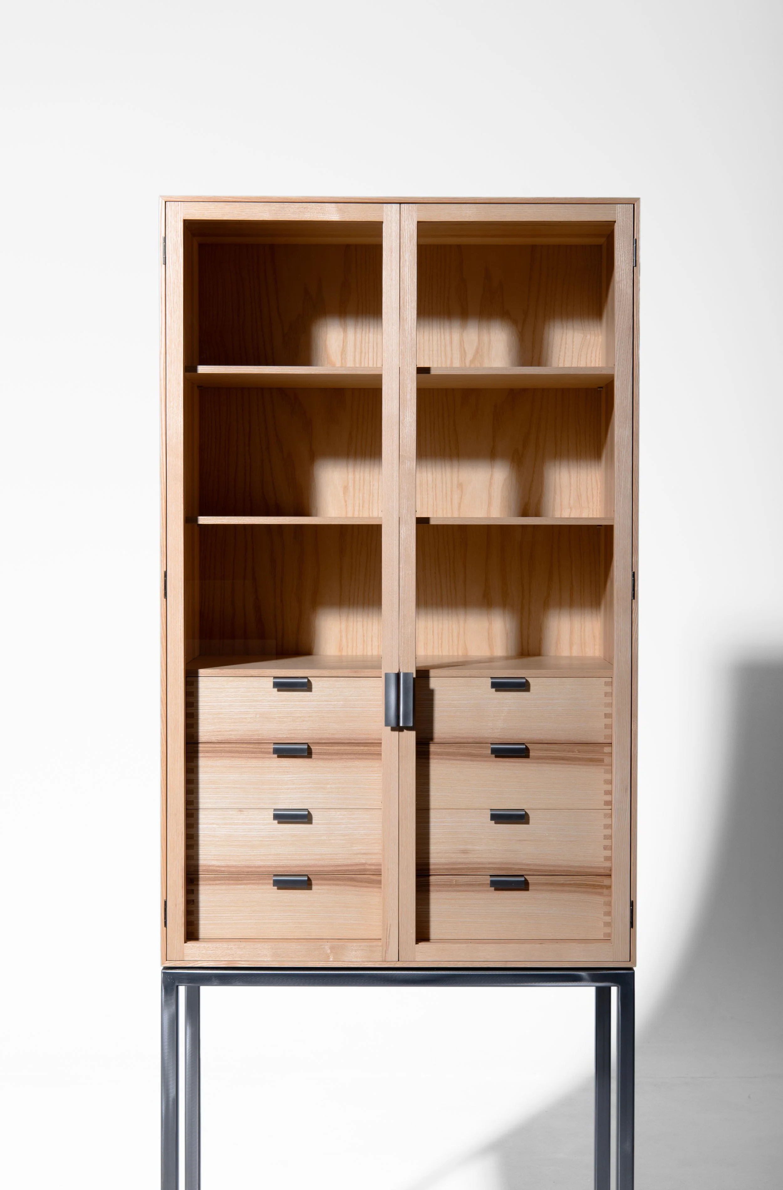 Ein Holzschrank mit Schubladen und offenen Fächern auf einem metallischen Stand.