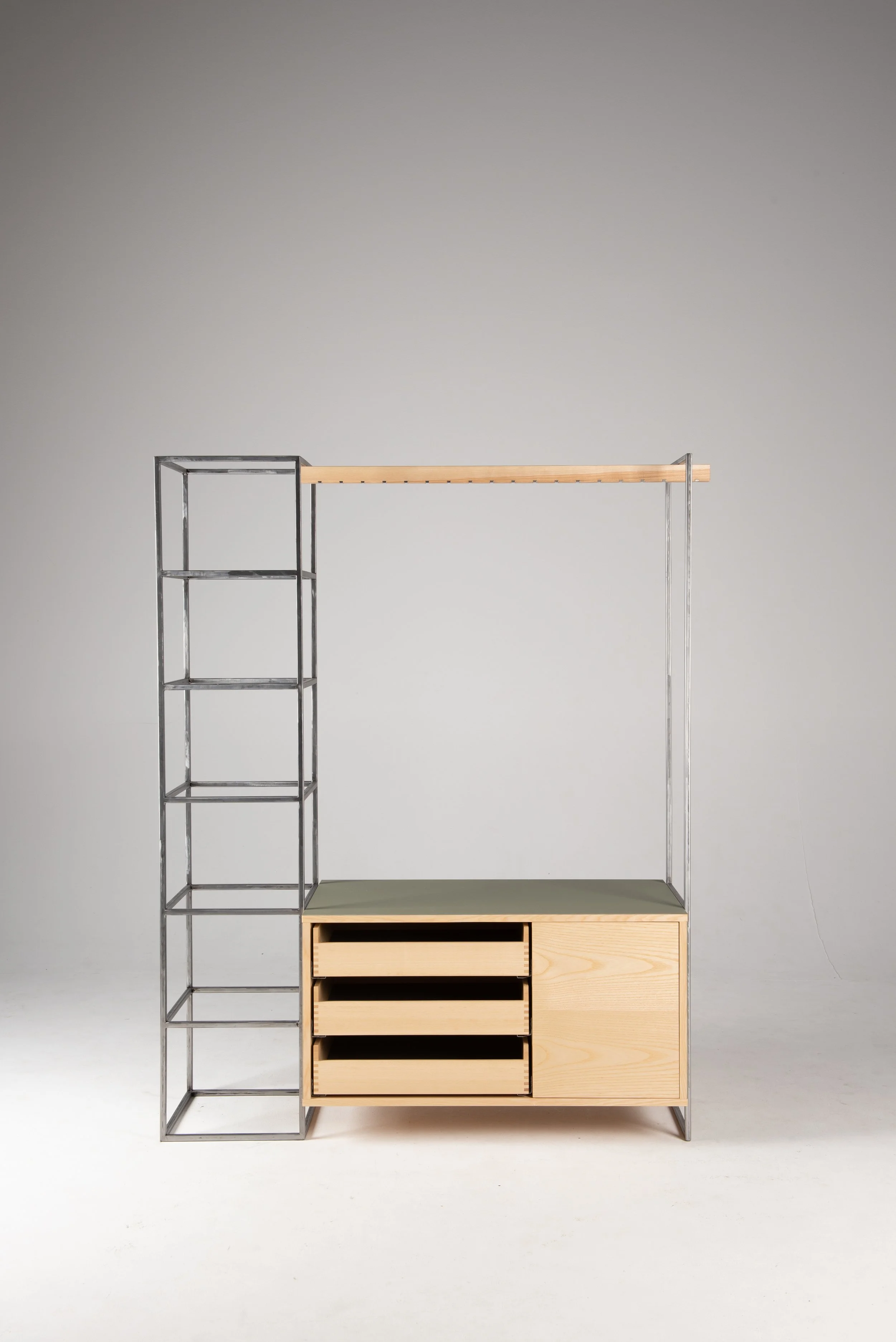 Ein modernes Möbelstück mit offenen Holzregalen, Schubladen, einer festen Oberfläche und einem vertikalen Stabrahmen, abgestellt vor einer neutralen Wand.