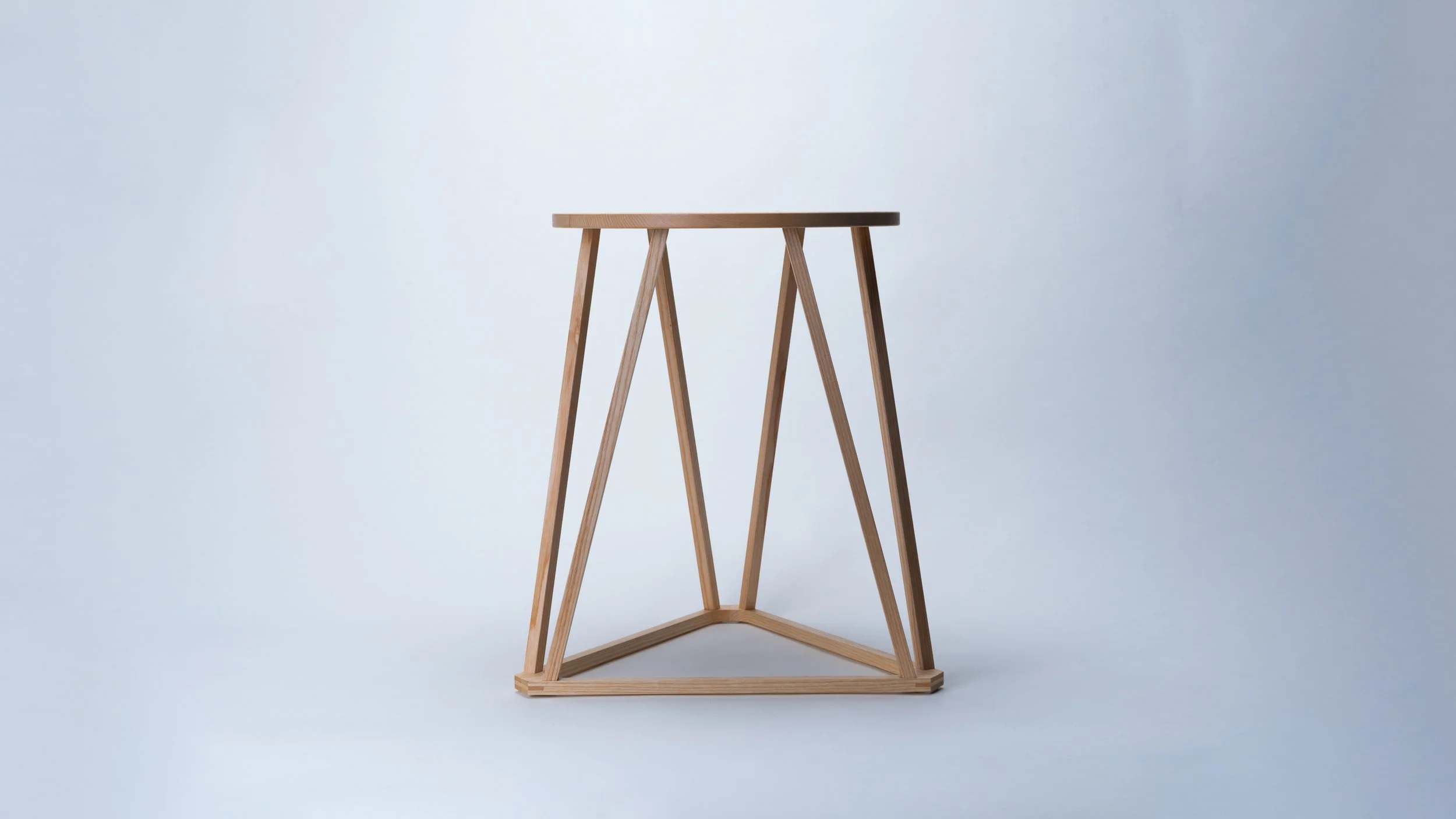 Moderner Beistelltisch aus Holz mit geometrischem Design auf heller Hintergrund.