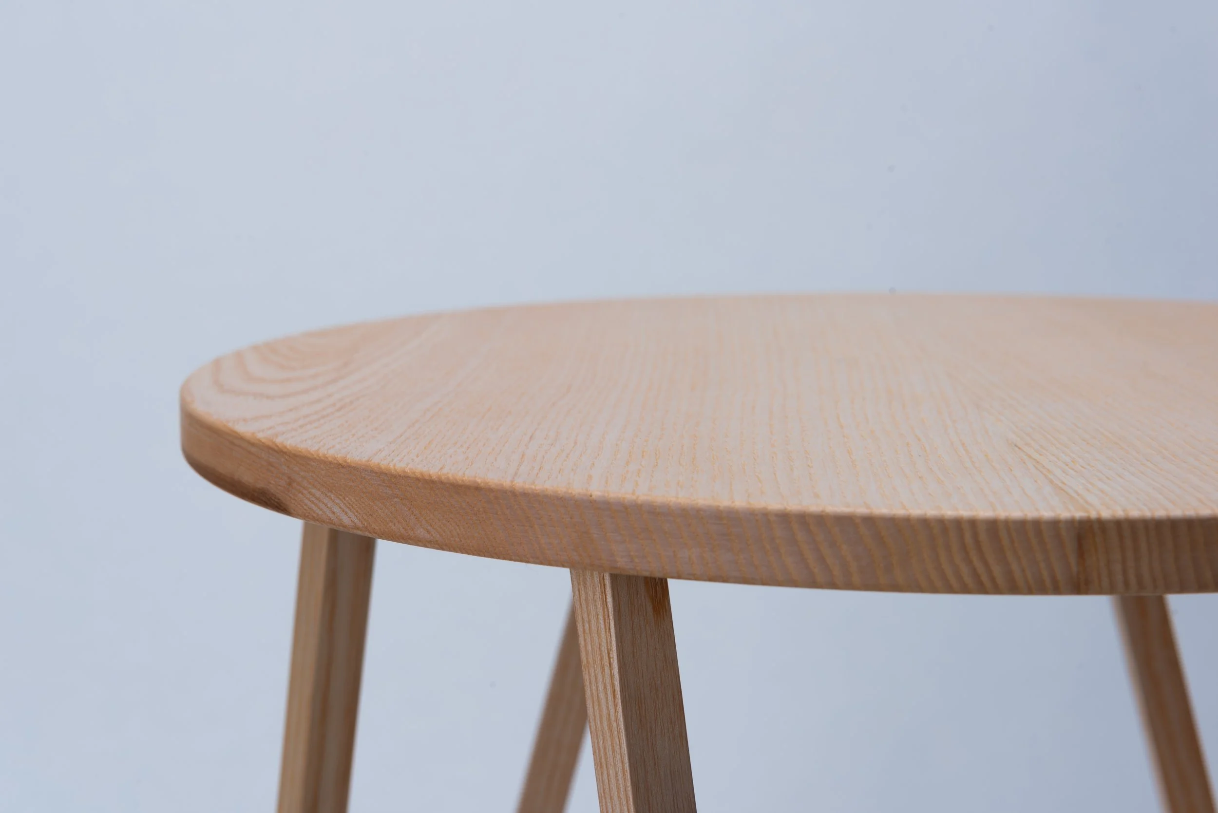 Nahaufnahme eines hölzernen Stuhls mit geschwungener Sitzfläche auf weißem Hintergrund.