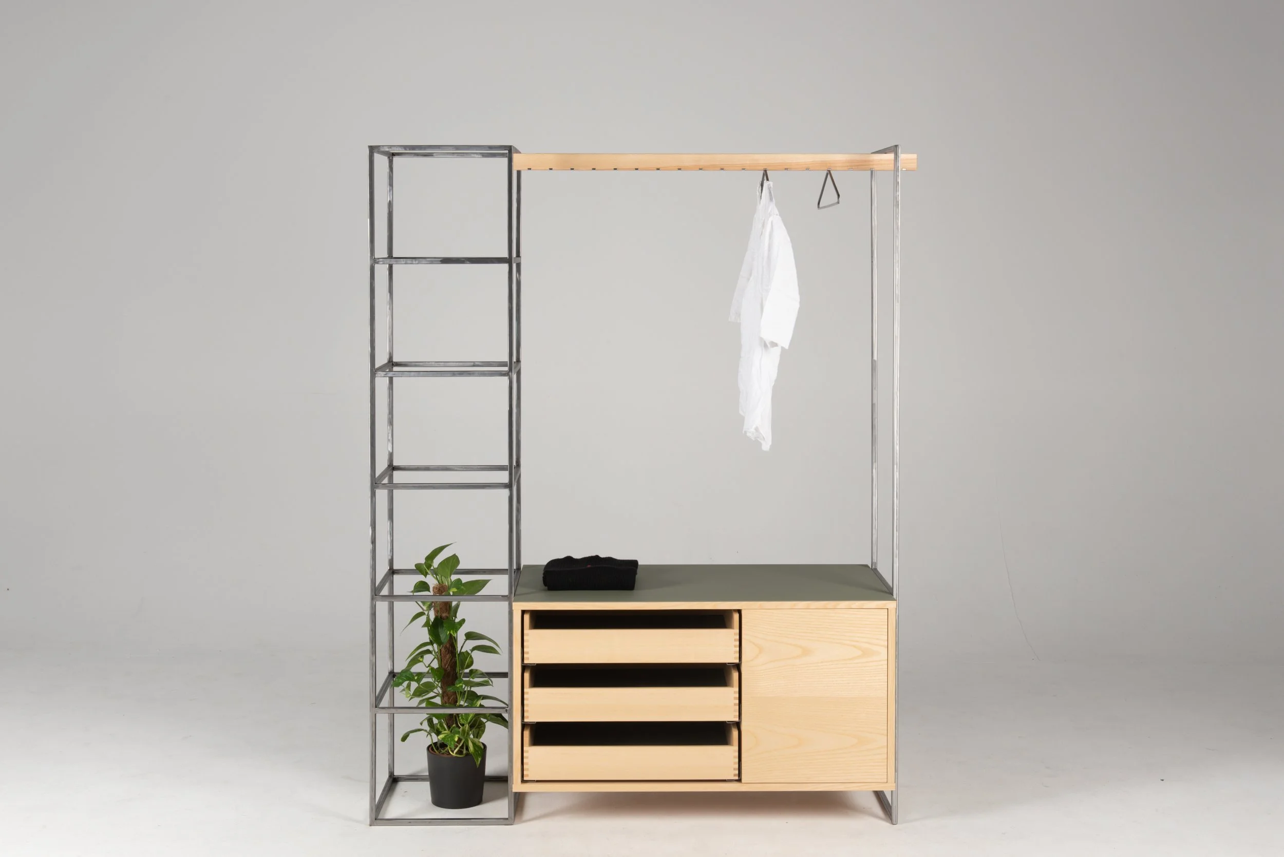 Moderner Kleiderschrank mit offenen Fächern, Kleiderstange, Pflanzen und Schubladen auf neutralem Hintergrund.