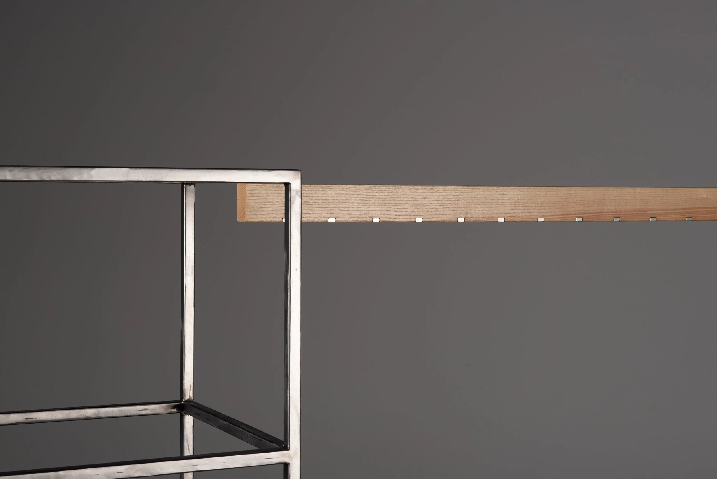 Ein minimalistisches, modernes Regal mit einem Metallrahmen und einer hölzernen Ablage gegen einen grauen Hintergrund.