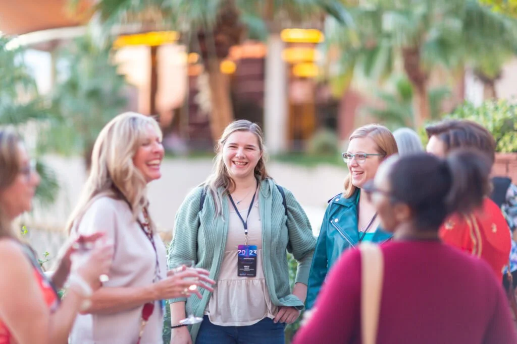 Group of people smiling and talking outdoors at a social event.