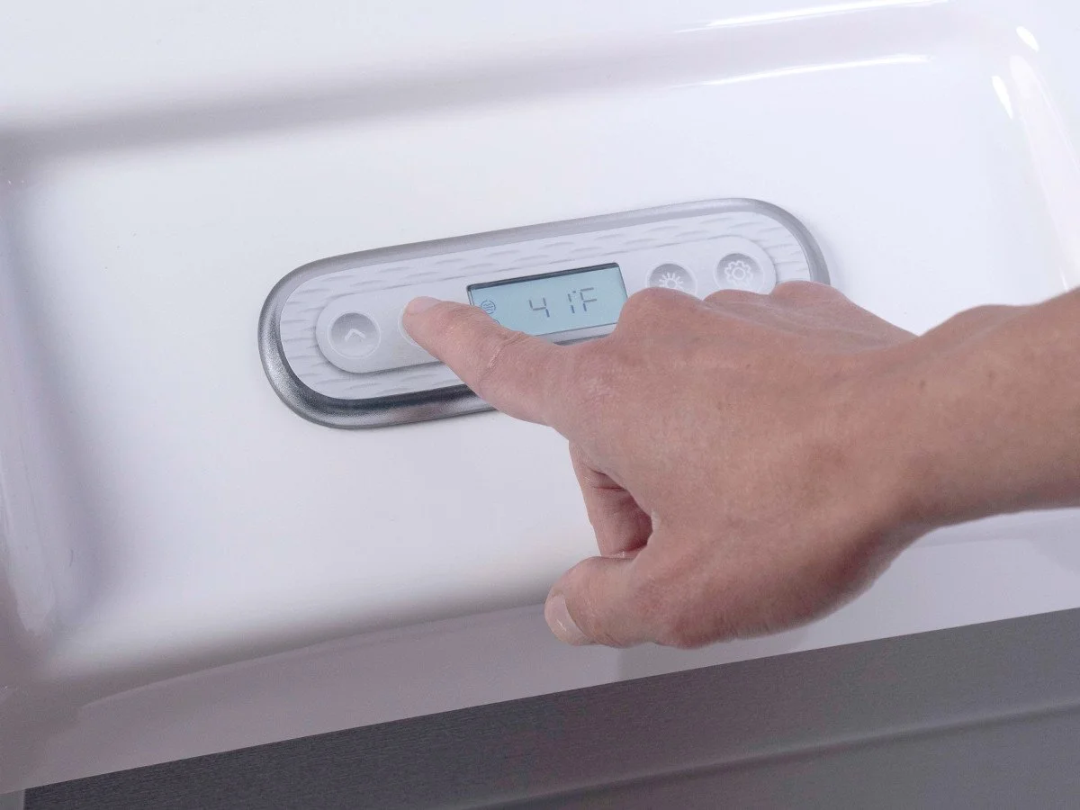 A person's hand is adjusting the temperature settings on a cold plunge control panel, which displays 41°F.