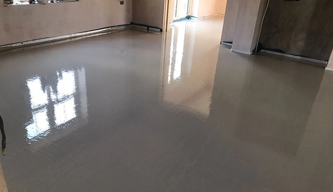 Vacant room with freshly poured polished concrete floor reflecting windows and interior lights.