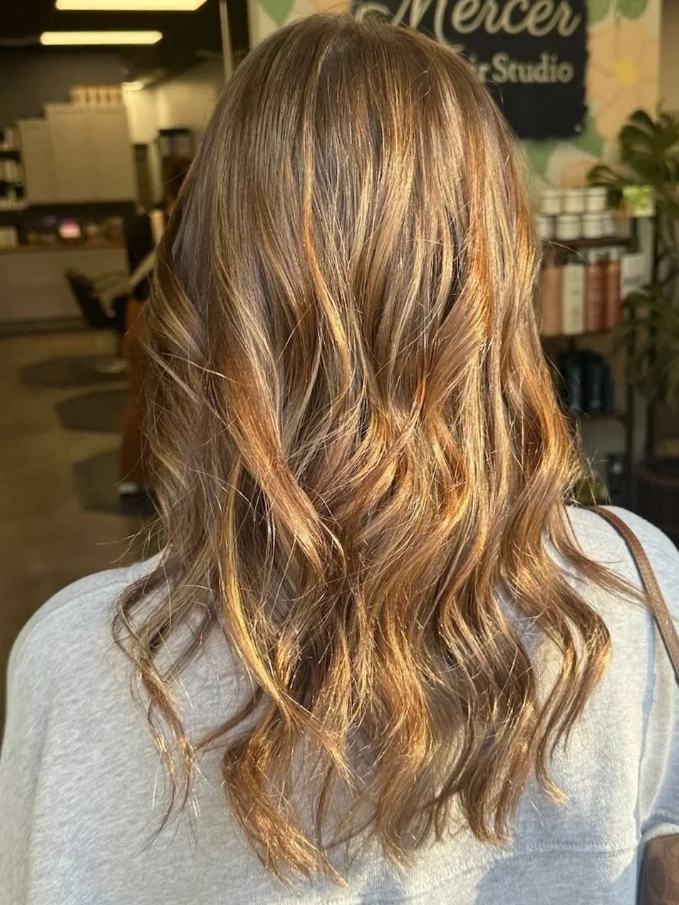 A modern backyard with a swimming pool, lounge chairs, trees, desert plants, and a house with an outdoor seating area.