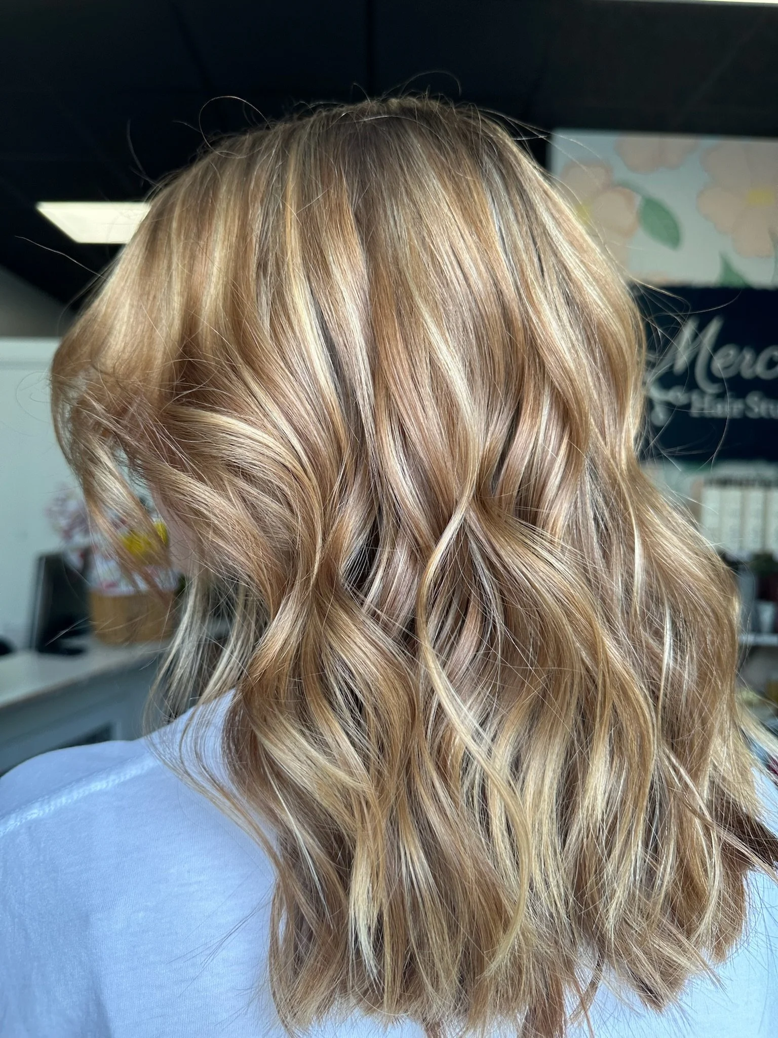 Wavy, blonde hair on a person, seen from the back, in a hair salon.