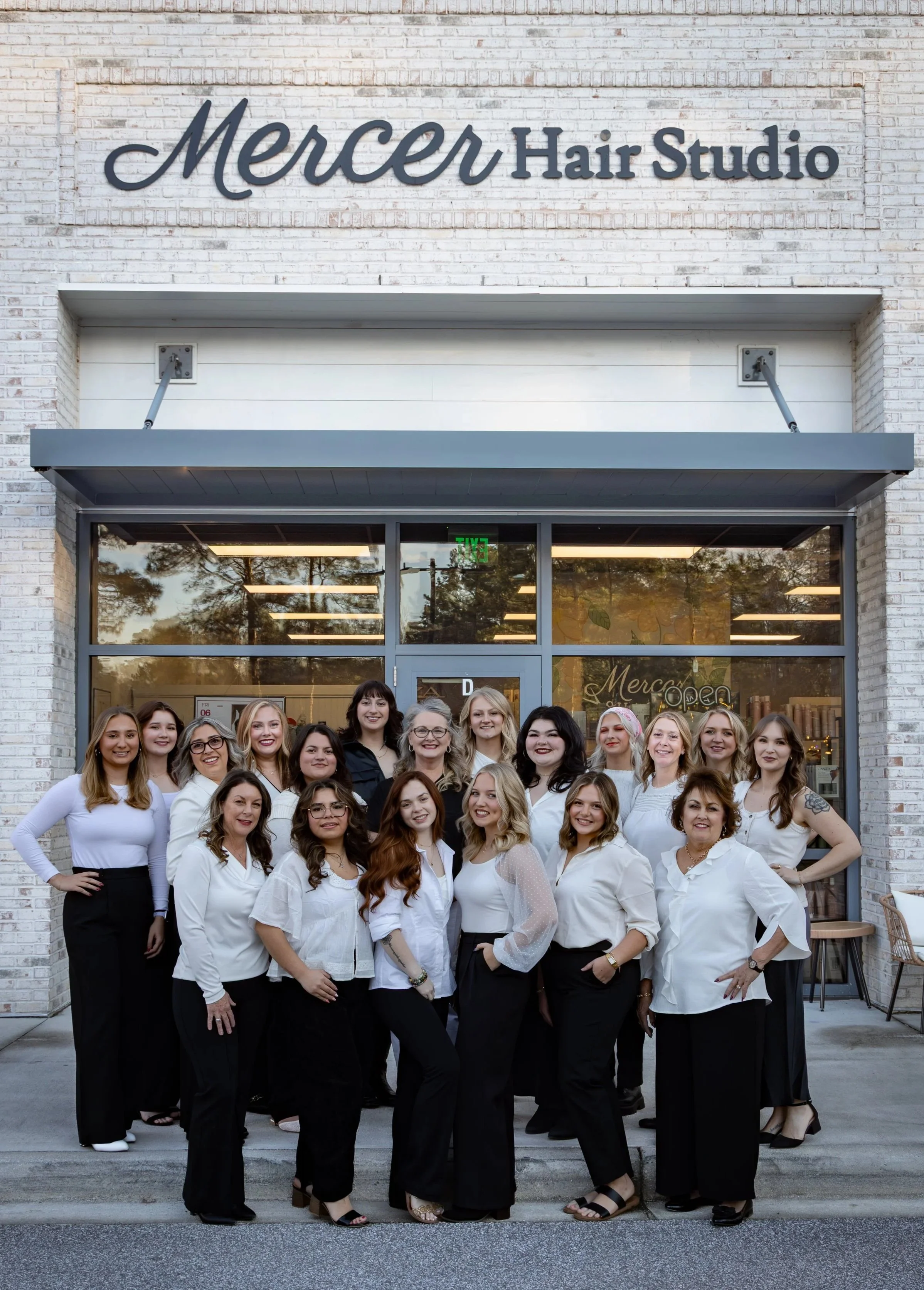 Group of women standing outside Mercer Hair Studio, posing for a photo.
