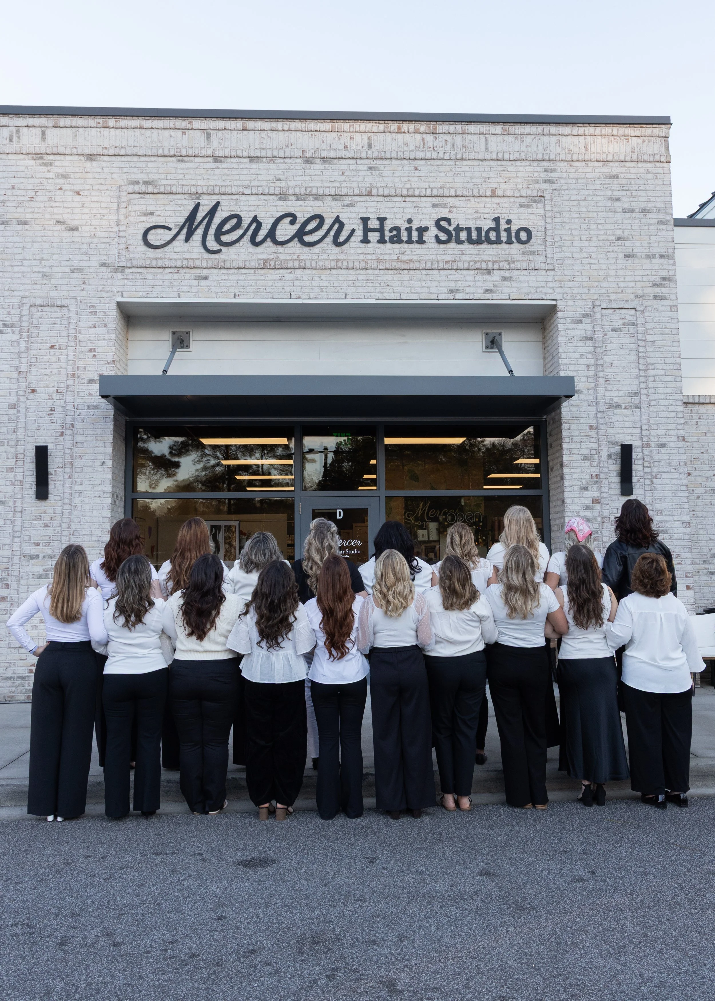 Group of women standing outside a hair studio called Mercer Hair Studio, facing the entrance.