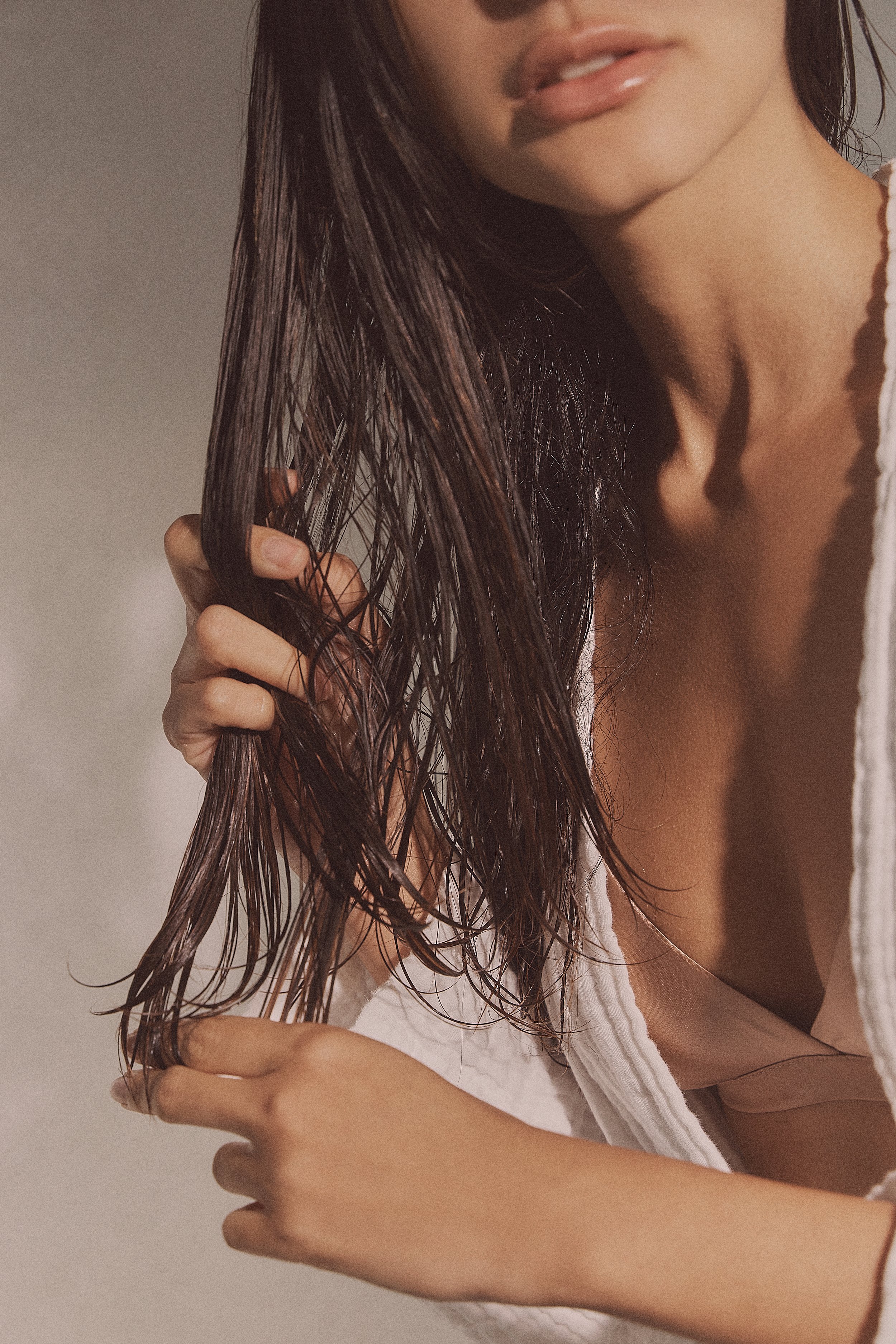A woman with wet hair brushing her hair with her hand.