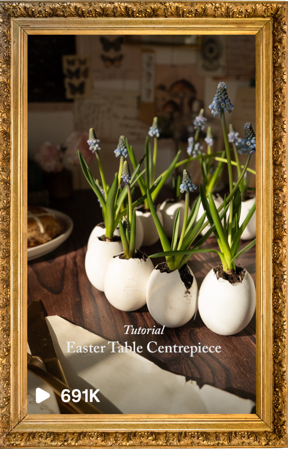 A tutorial video thumbnail showing a creative Easter table centerpiece made with eggs and hyacinth flowers arranged in white eggshells on a wooden table. Blog writer and website designer.