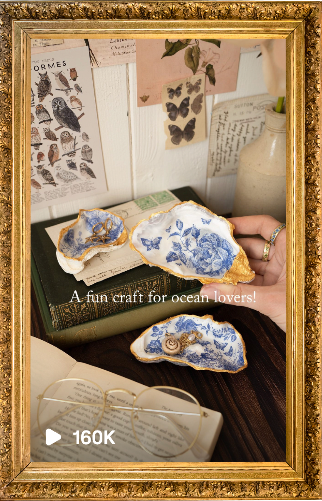 Decorative ocean-themed craft display with blue and white shell dishes, gold jewelry, framed butterfly prints, a vintage book, glasses, and botanical notes in the background. Craft blogs and email marketing support in cornwall and remotely.