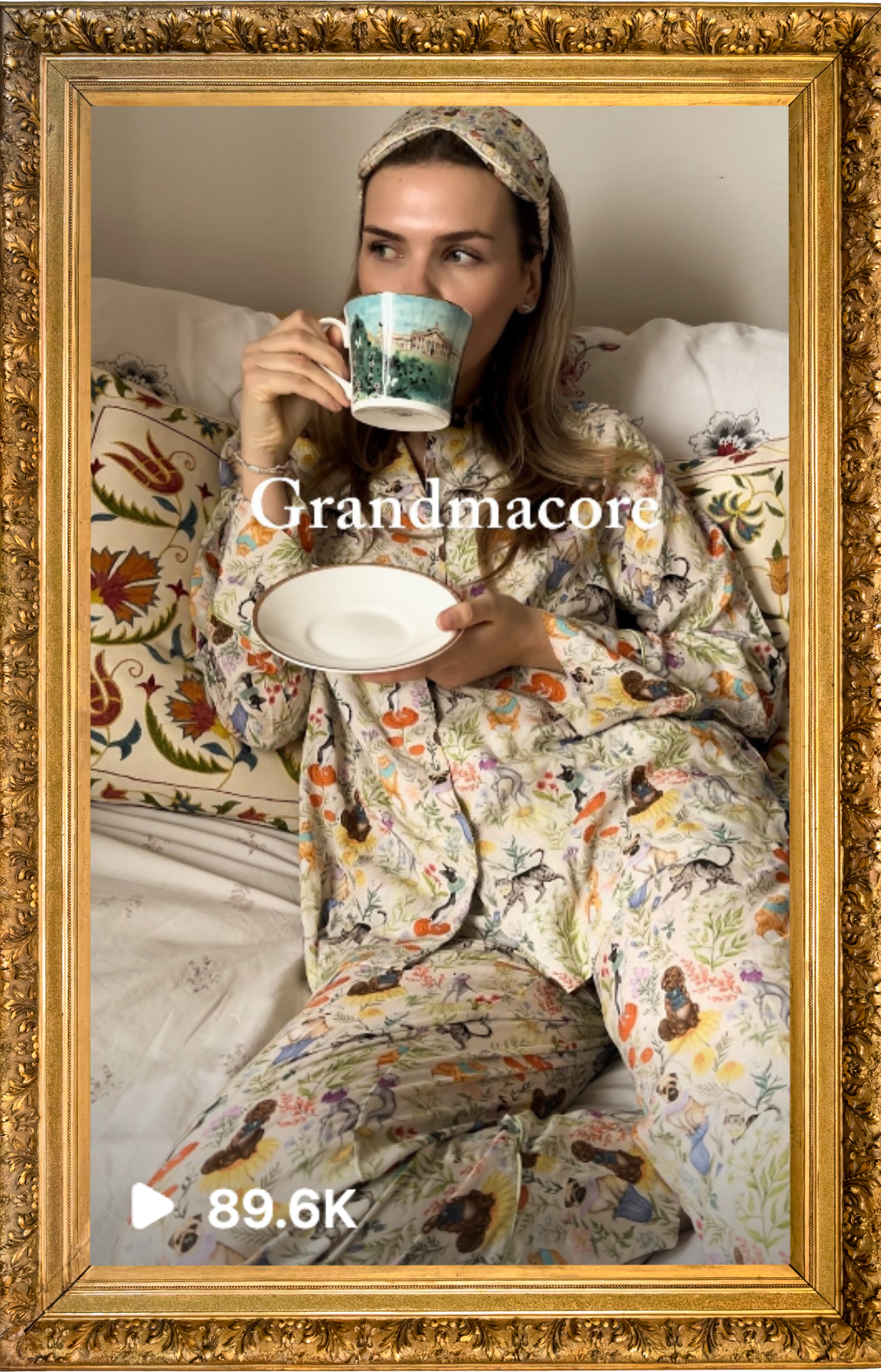 A woman in floral pajamas sitting on a bed, holding a teacup to her mouth with one hand and a saucer in the other. She is wearing a headscarf and appears to be in a cozy indoor setting. The image is framed with an ornate gold border and has the word 
