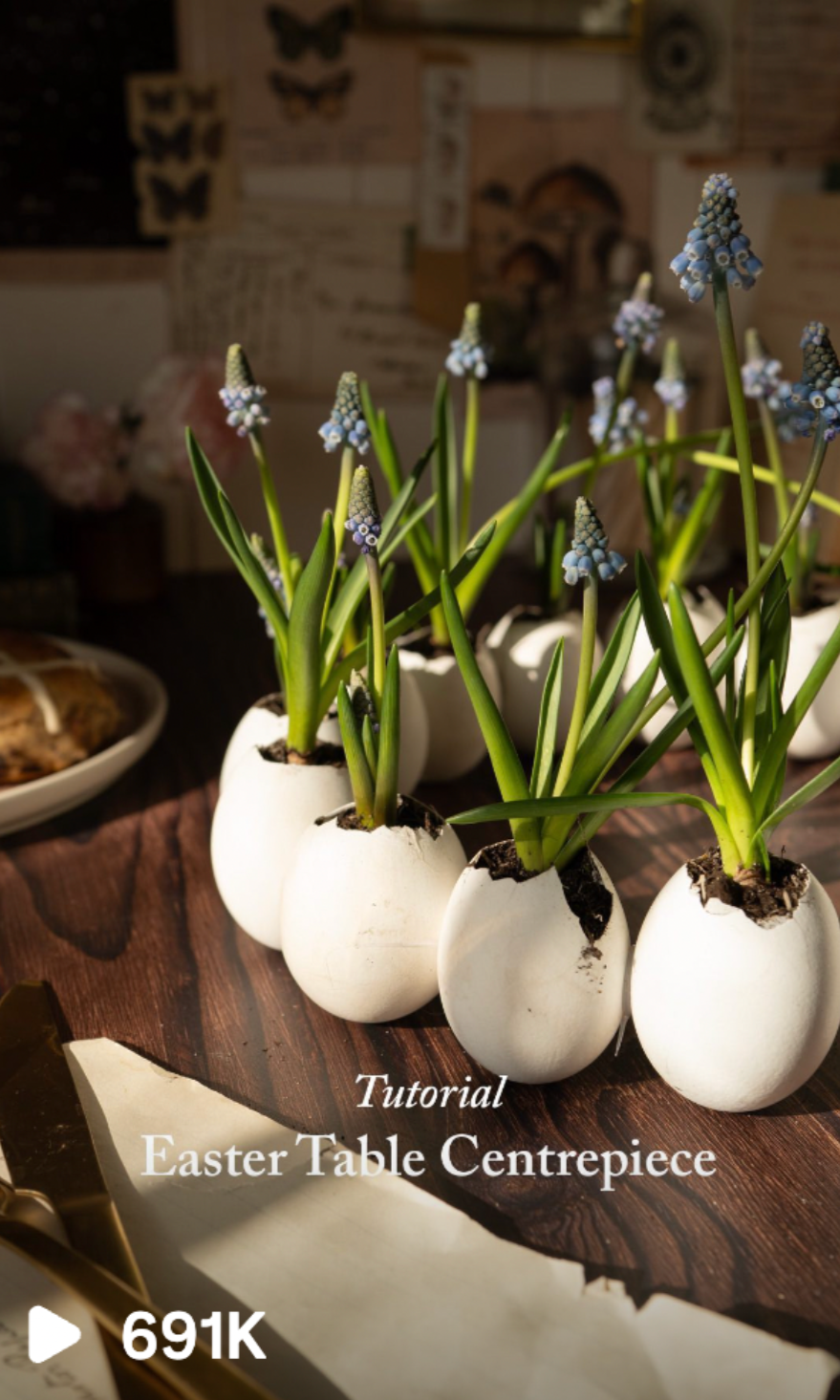 A row of potted hyacinth flowers in white egg-shaped planters on a wooden table, with Easter-themed decorations in the background. Craft content creation and blog post writer in cornwall.