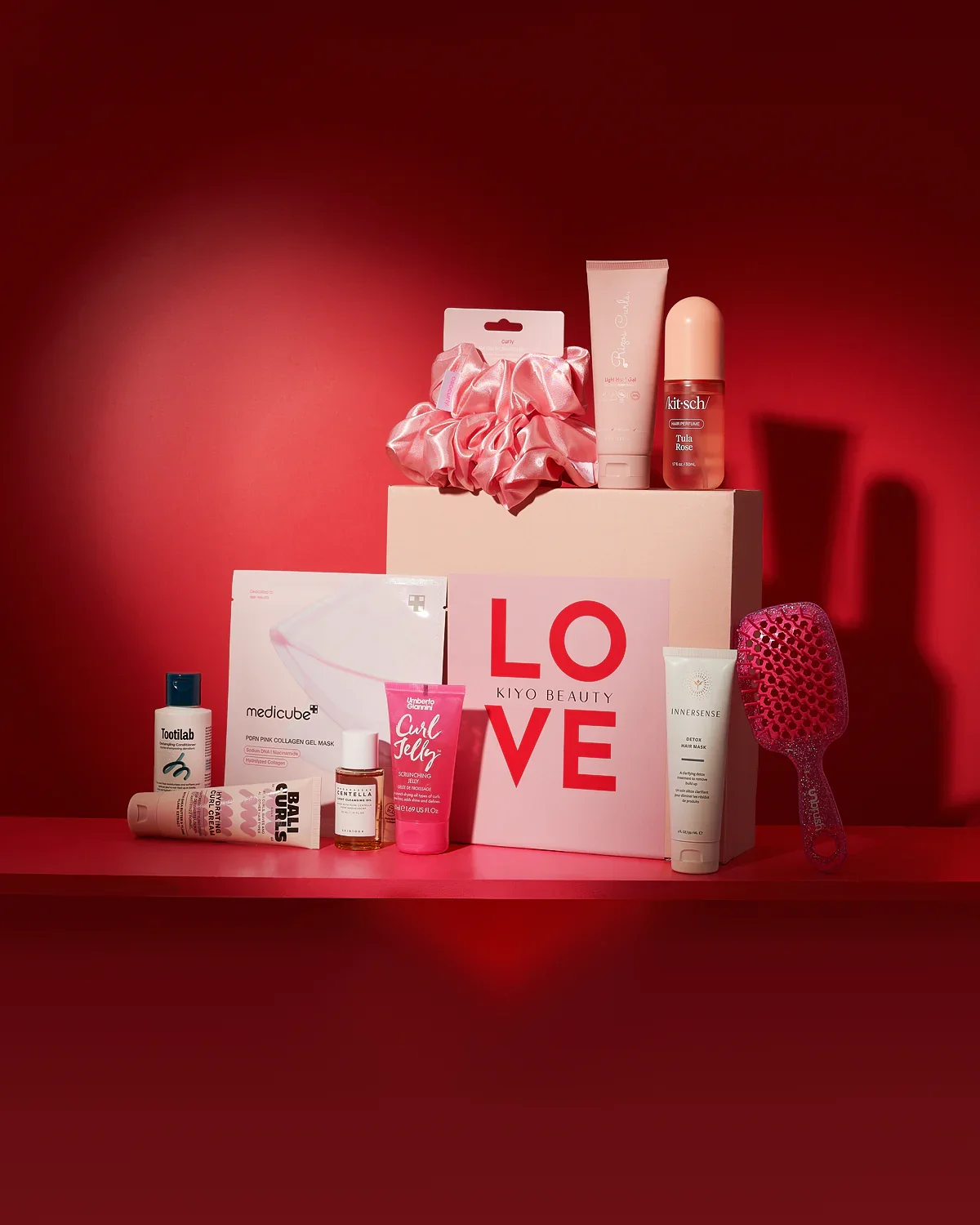 Collection of beauty and skincare products on a pink and red background with a Kiyo Beauty box and LOVE sign. Social media strategist.