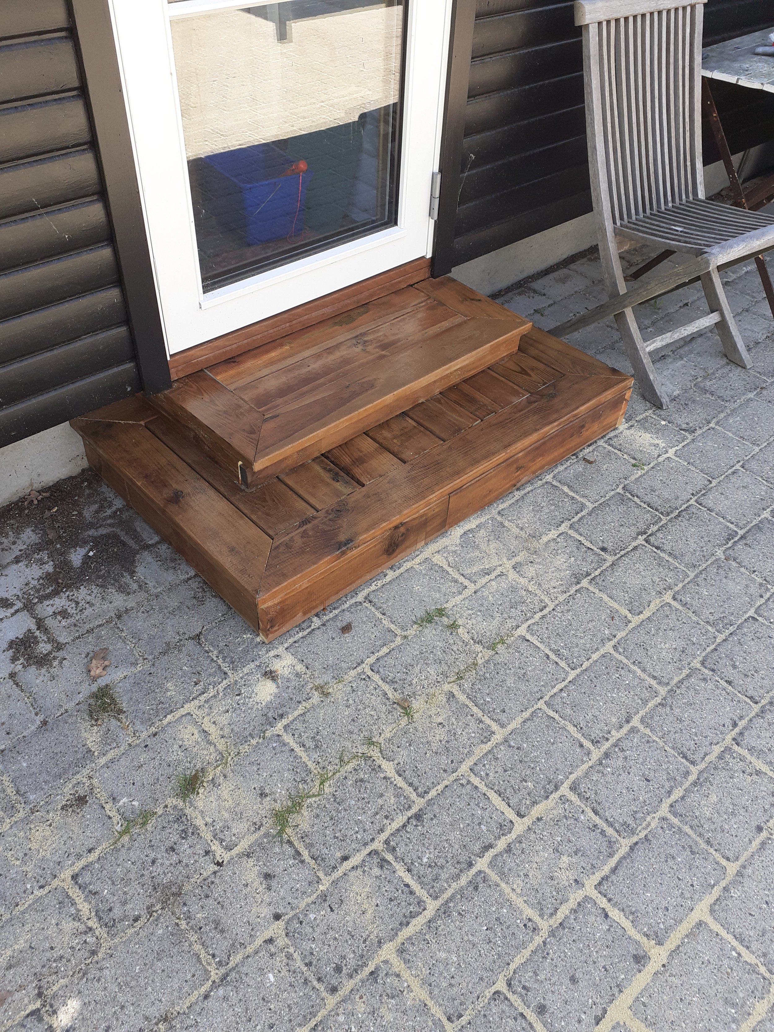 Trætrin foran skydedør med tilhørende terrasseområde og stenbelægning.