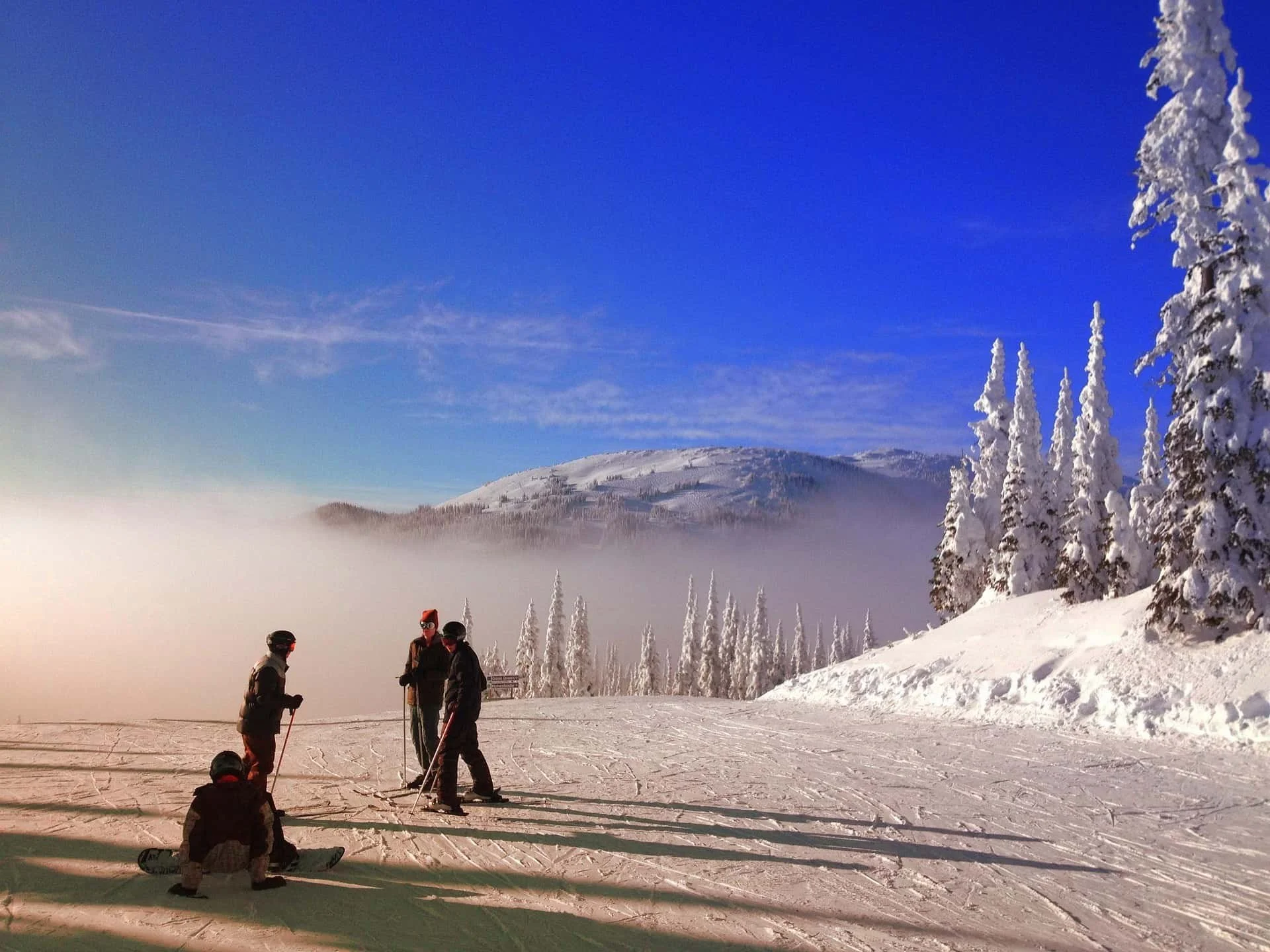 3 skiers and 1 snowboarder talking and planning route down the mountain