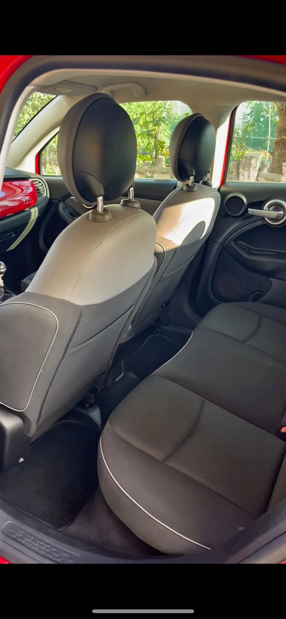 Interno di un'auto con due sedili anteriori e due sedili posteriori, con poggiatesta neri e interni in tonalità grigia, visuale dall'alto.