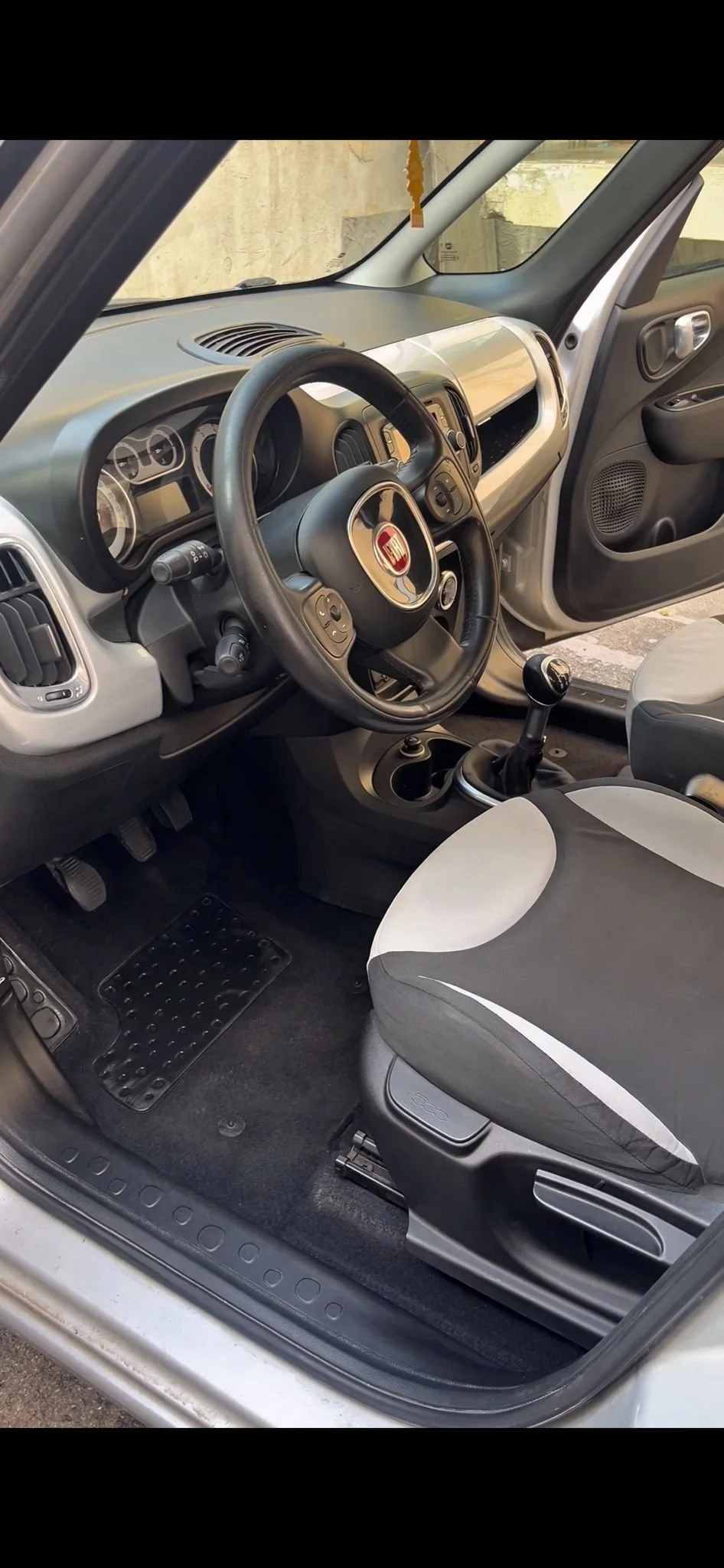 Interno di un'auto con volante, cambio manual, sedili e cruscotto, marca Fiat.