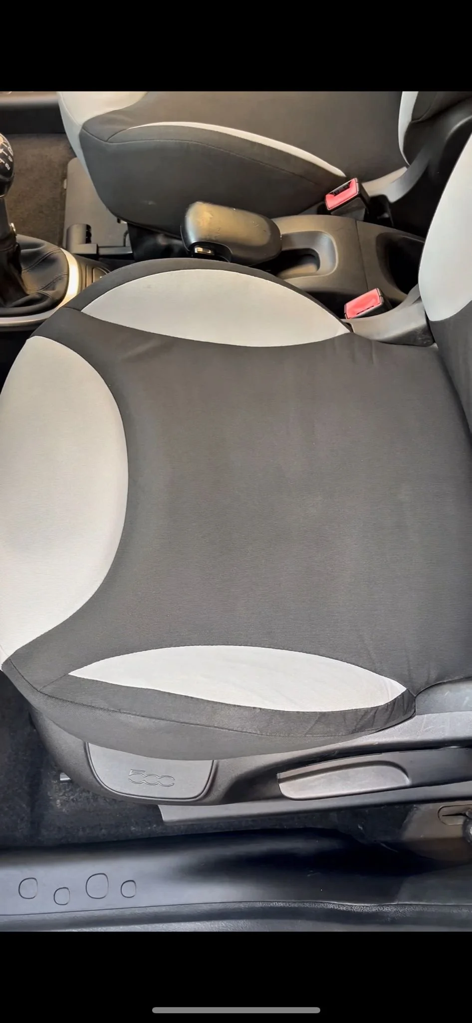 Sedile anteriore di un'auto con cuscino nero e rivestimento in tessuto chiaro, parte del veicolo Fiat 500.