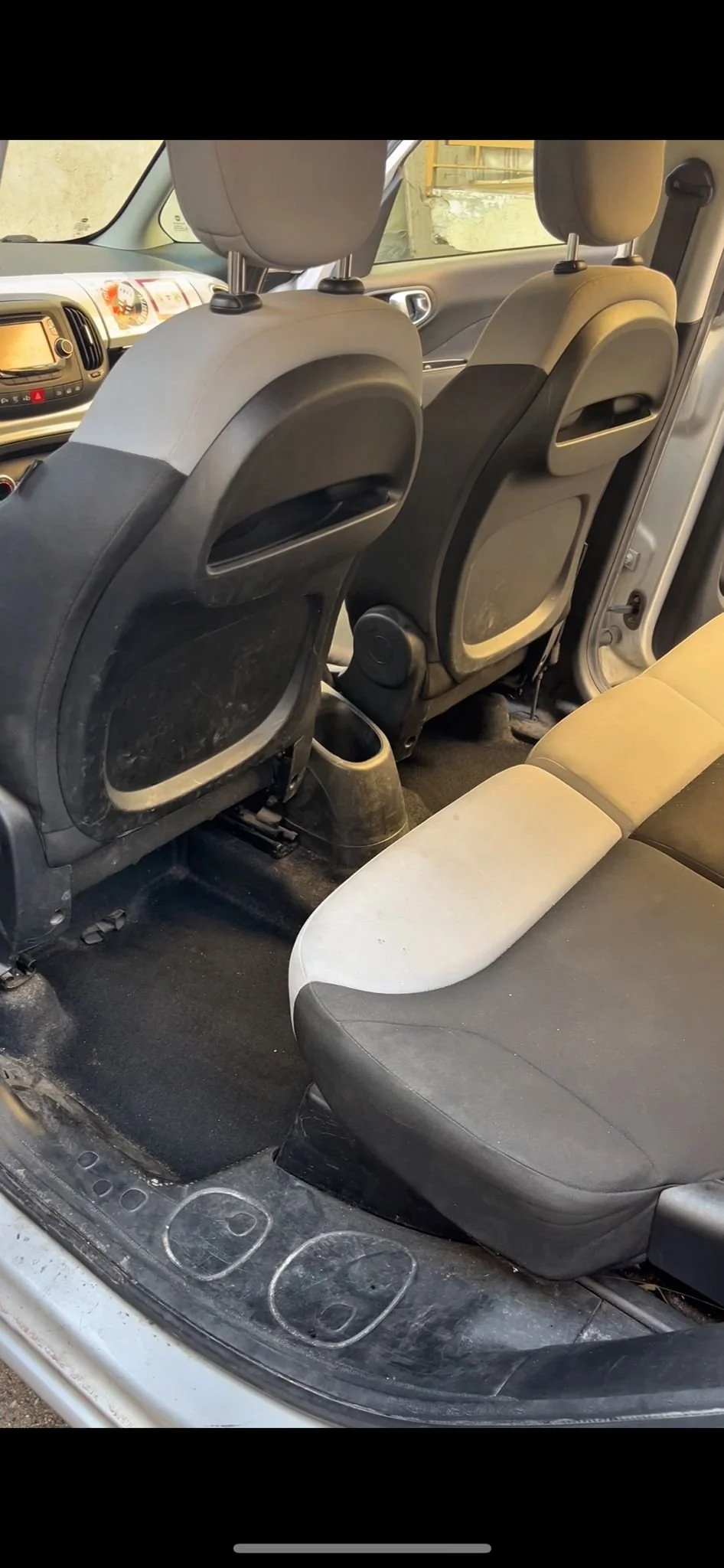 Interior di un'auto usata, con sedili e pavimento sporchi, e spazio tra i sedili anteriori e posteriori.