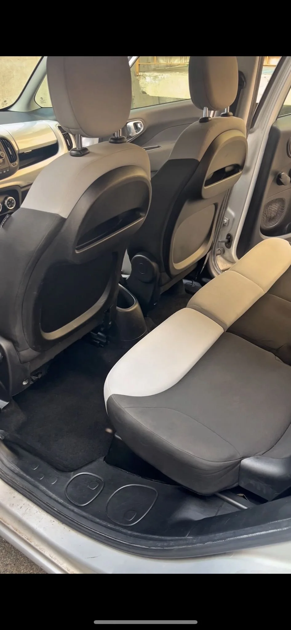 Interno di un'auto con sedili anteriori e posteriori, pannelli delle porte e tappezzeria in tonalità grigia e beige.