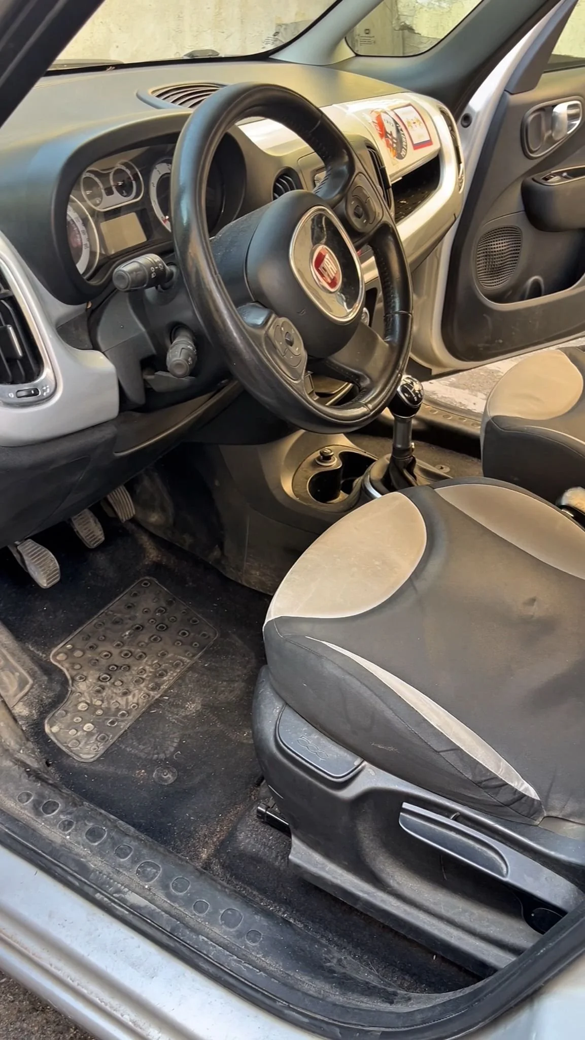 Interno di un'auto con volante, cambio manual, sedili e cruscotto