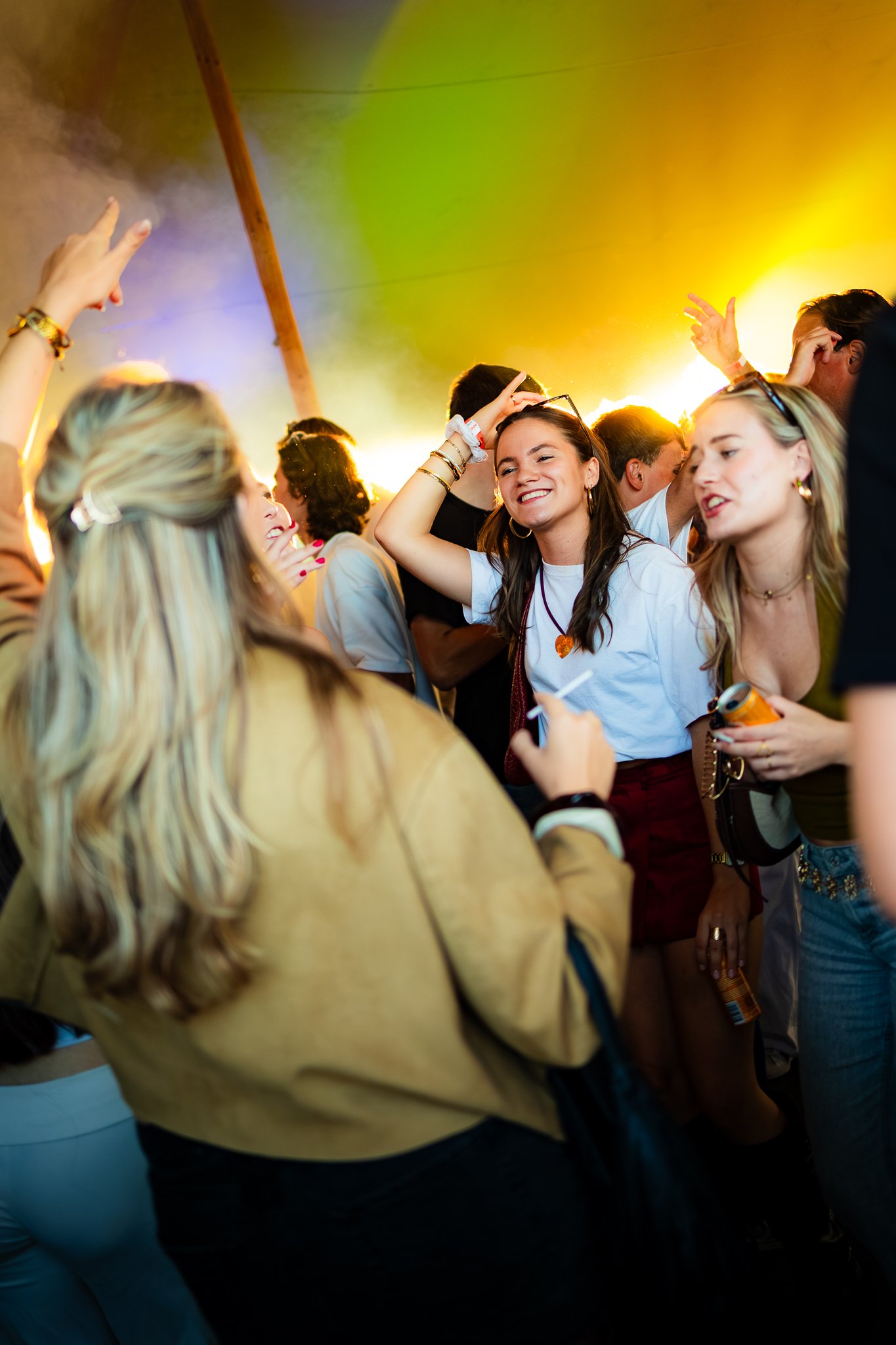 Group of young people dancing and having fun at a party with colorful lighting.