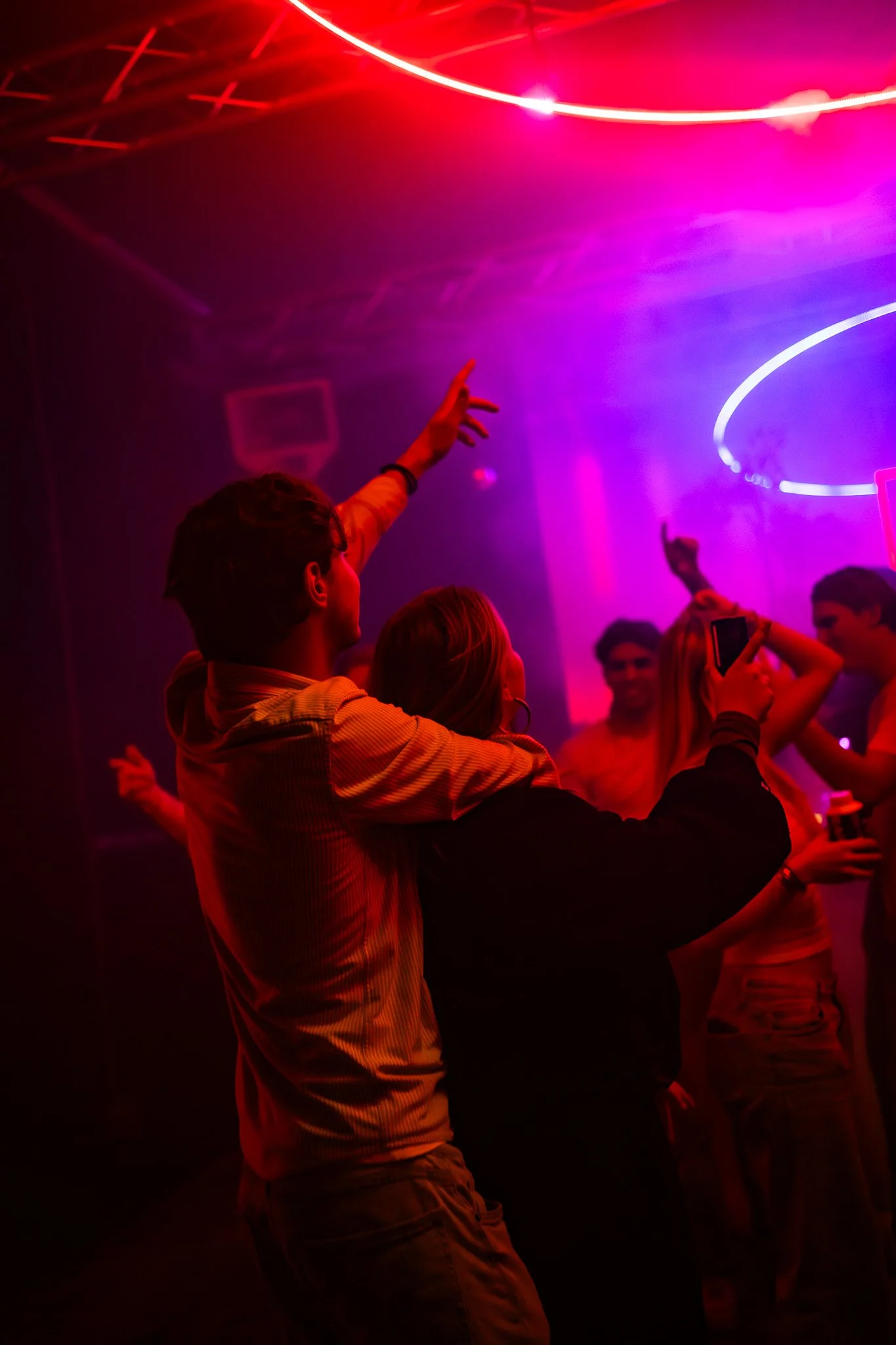 People dancing and enjoying at a nightclub with colorful neon lighting.