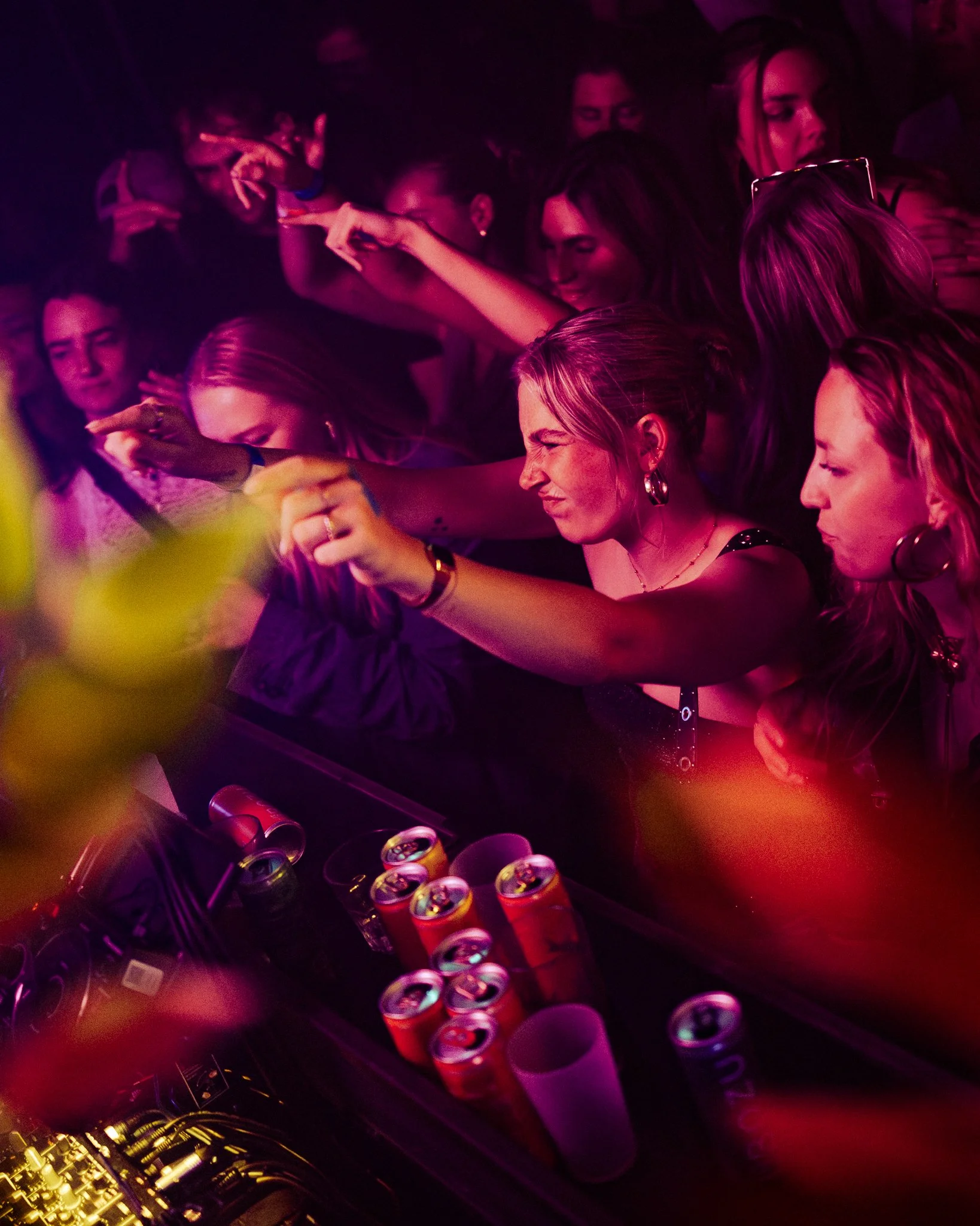 People dancing and enjoying music at a nightclub or party with colored lighting.