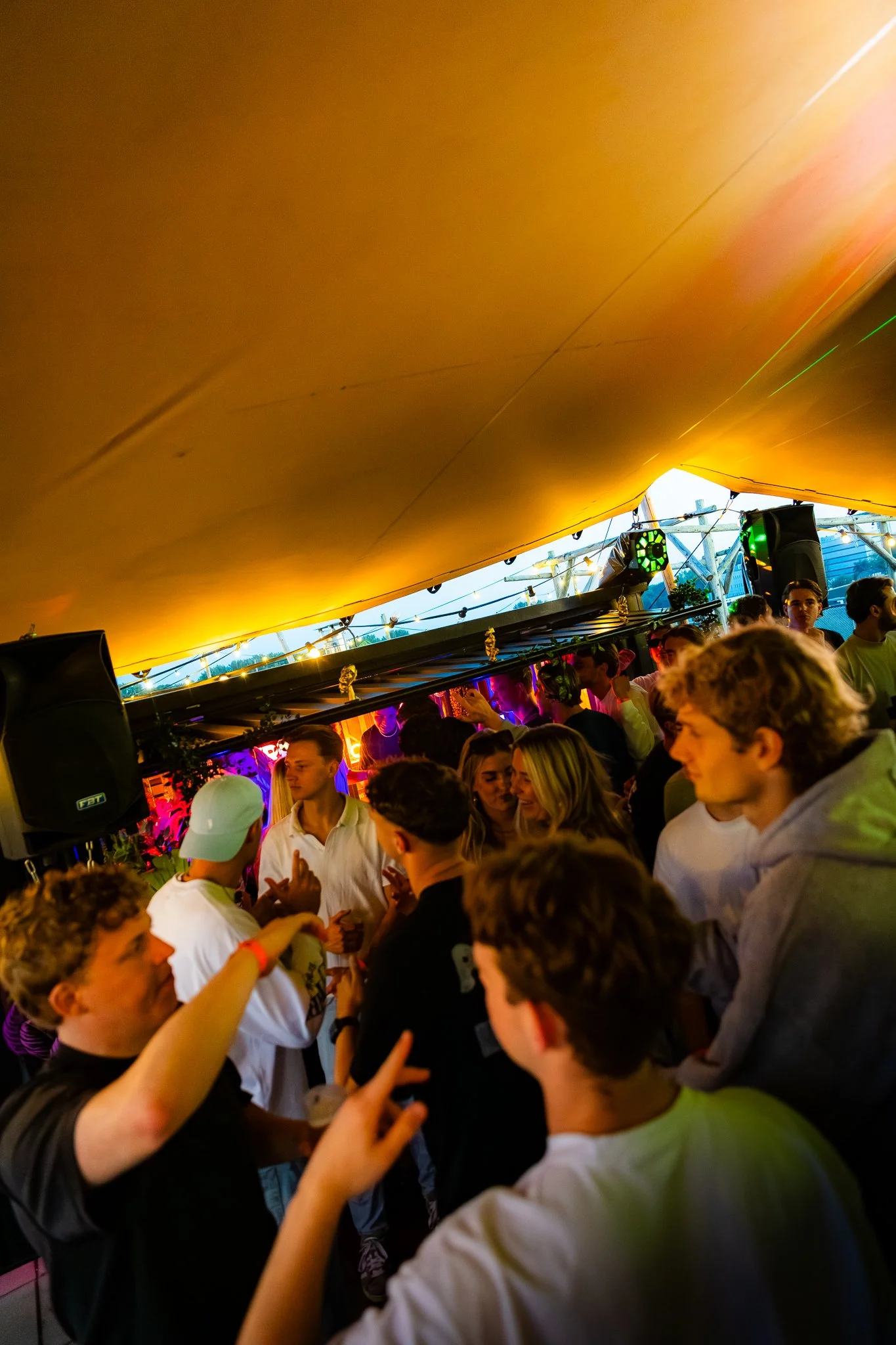 Group of young people dancing and socializing at a lively indoor party with colorful lighting