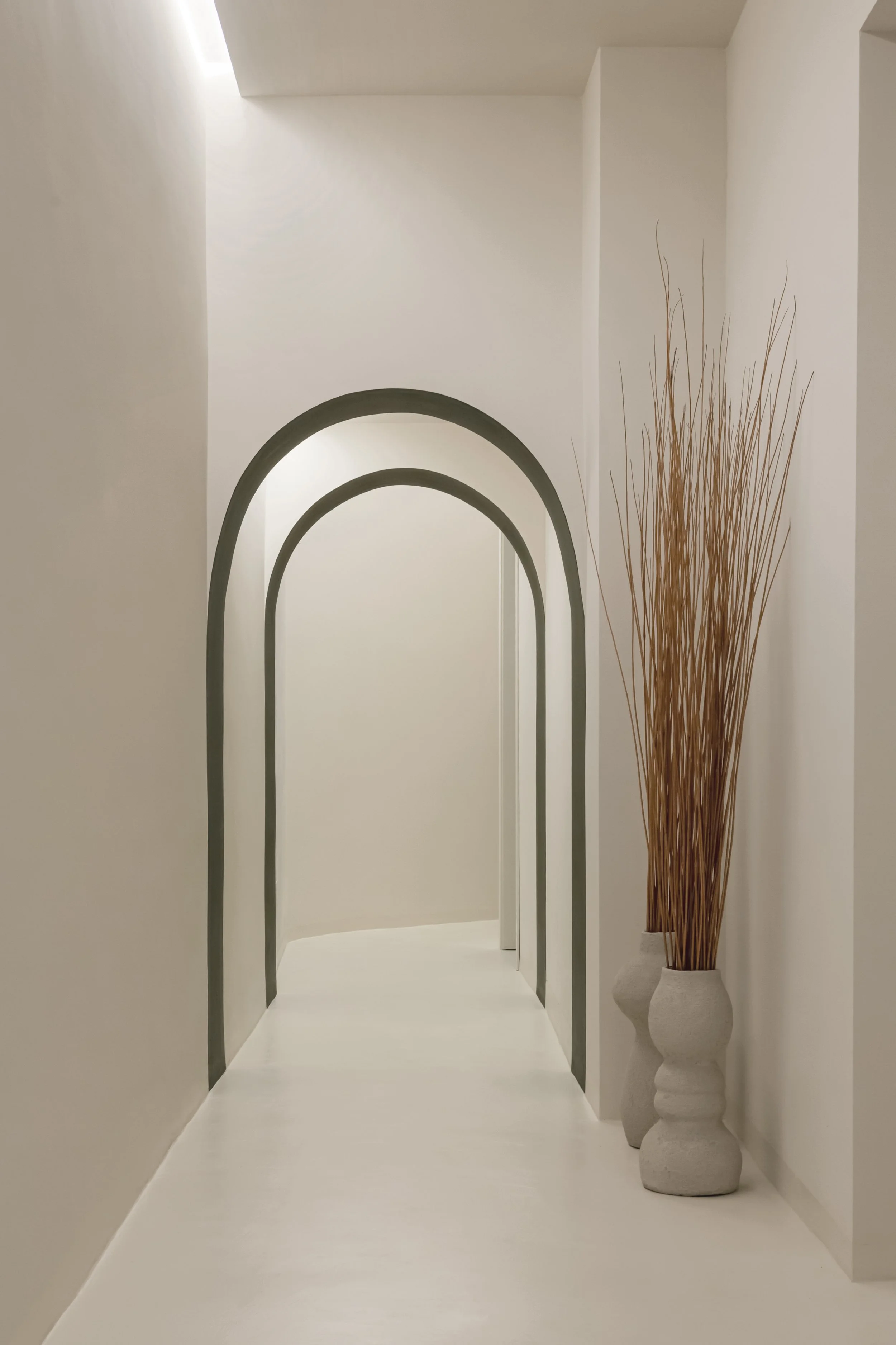Corridor minimalista con arco e vasi con rami secchi