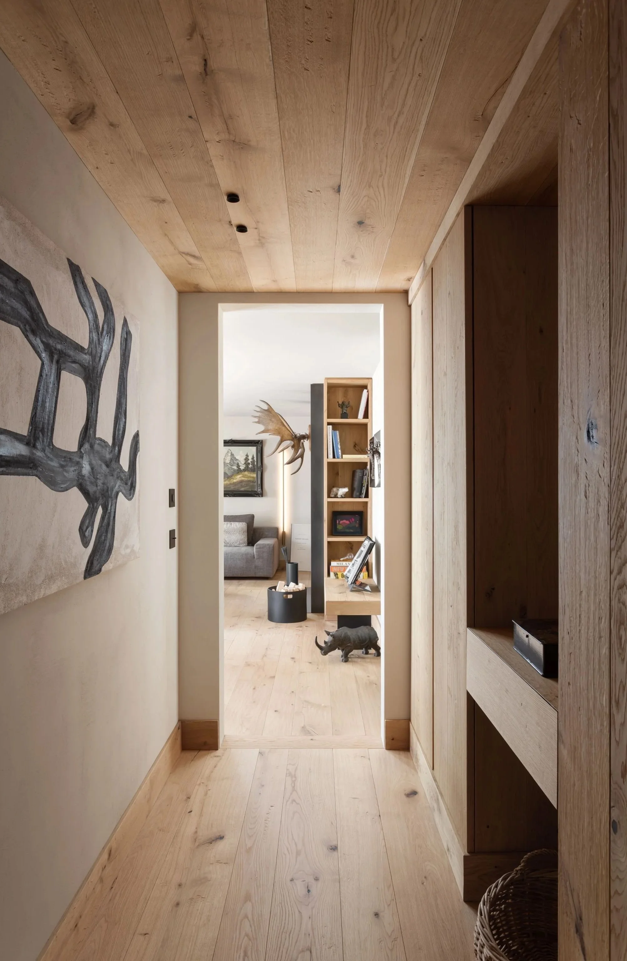 Vista di un corridoio in stile rustico con pareti e pavimenti in legno naturali, decorato con un quadro e arredi in legno.