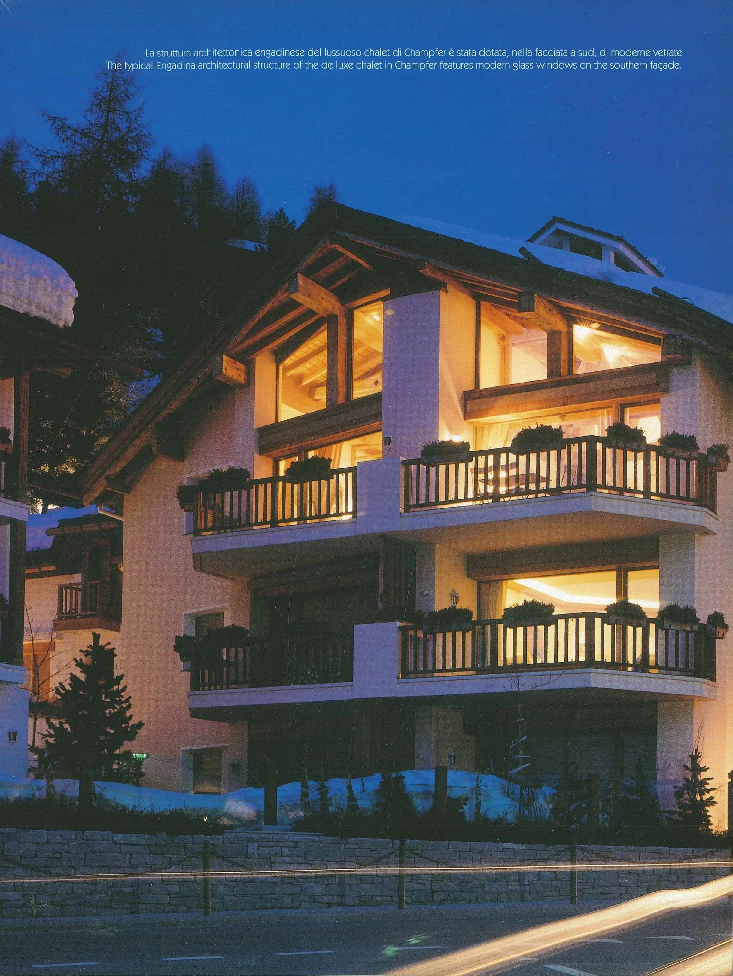 Immagine di un chalet di lusso con finestre di vetro moderne e balconi con gruppi di piante. L'edificio è illuminato dall'interno e si trova in una zona con neve sul terreno.