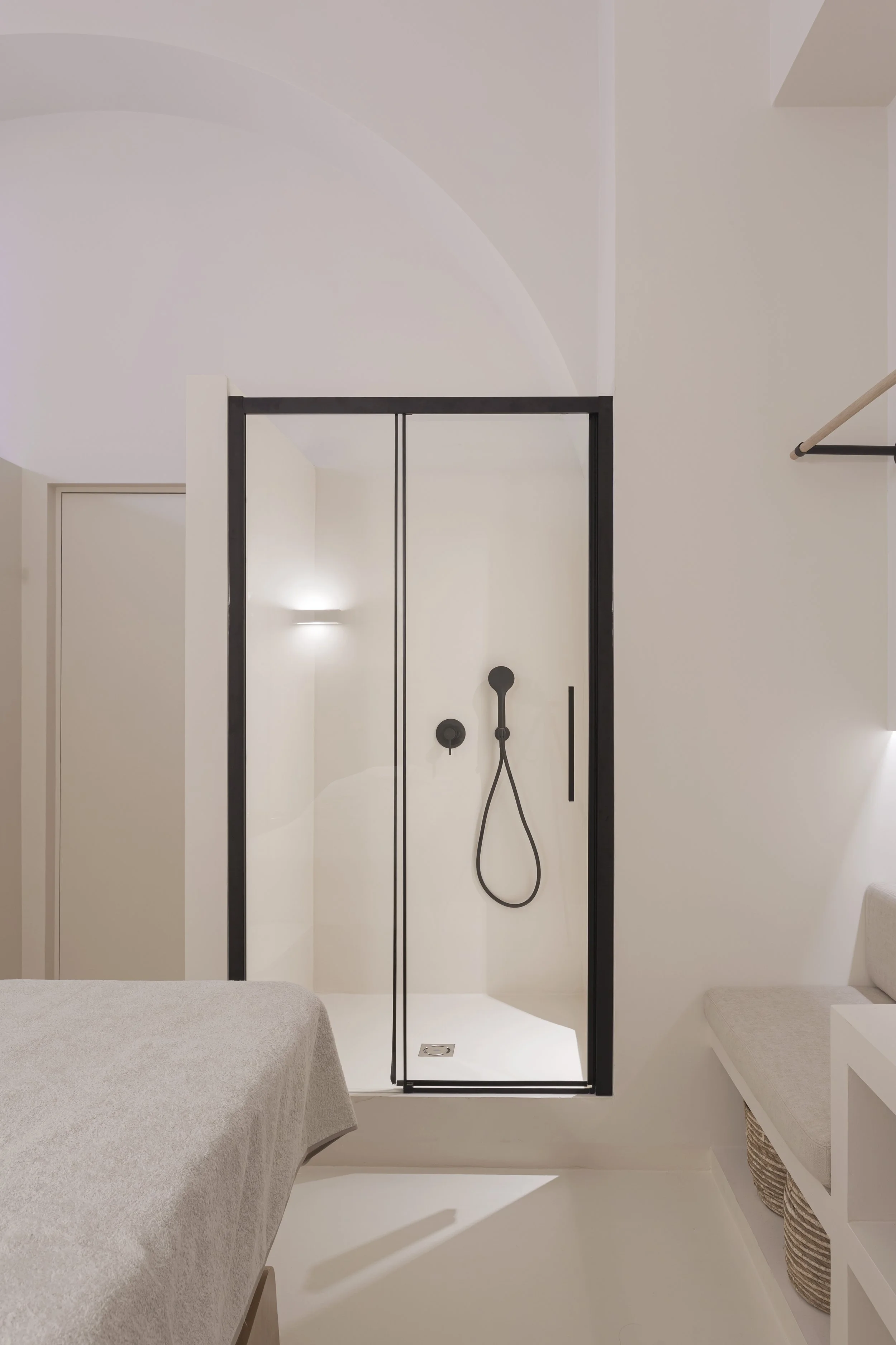 Doccia moderna con pareti di vetro e rubinetto nero in una camera da letto minimalista.