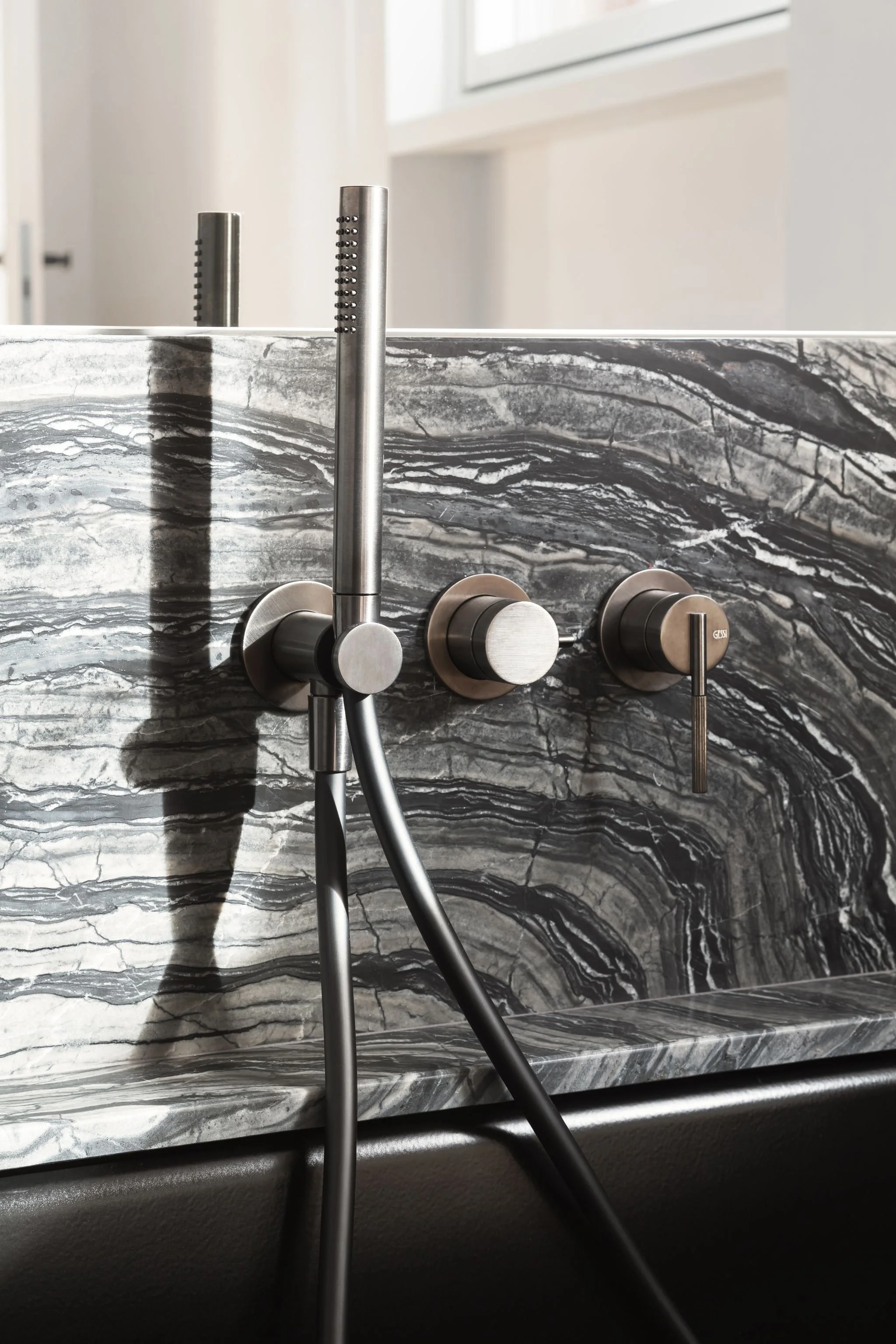 Dettaglio di rubinetti da bagno in acciaio inox con back panel in marmo grigio e nero