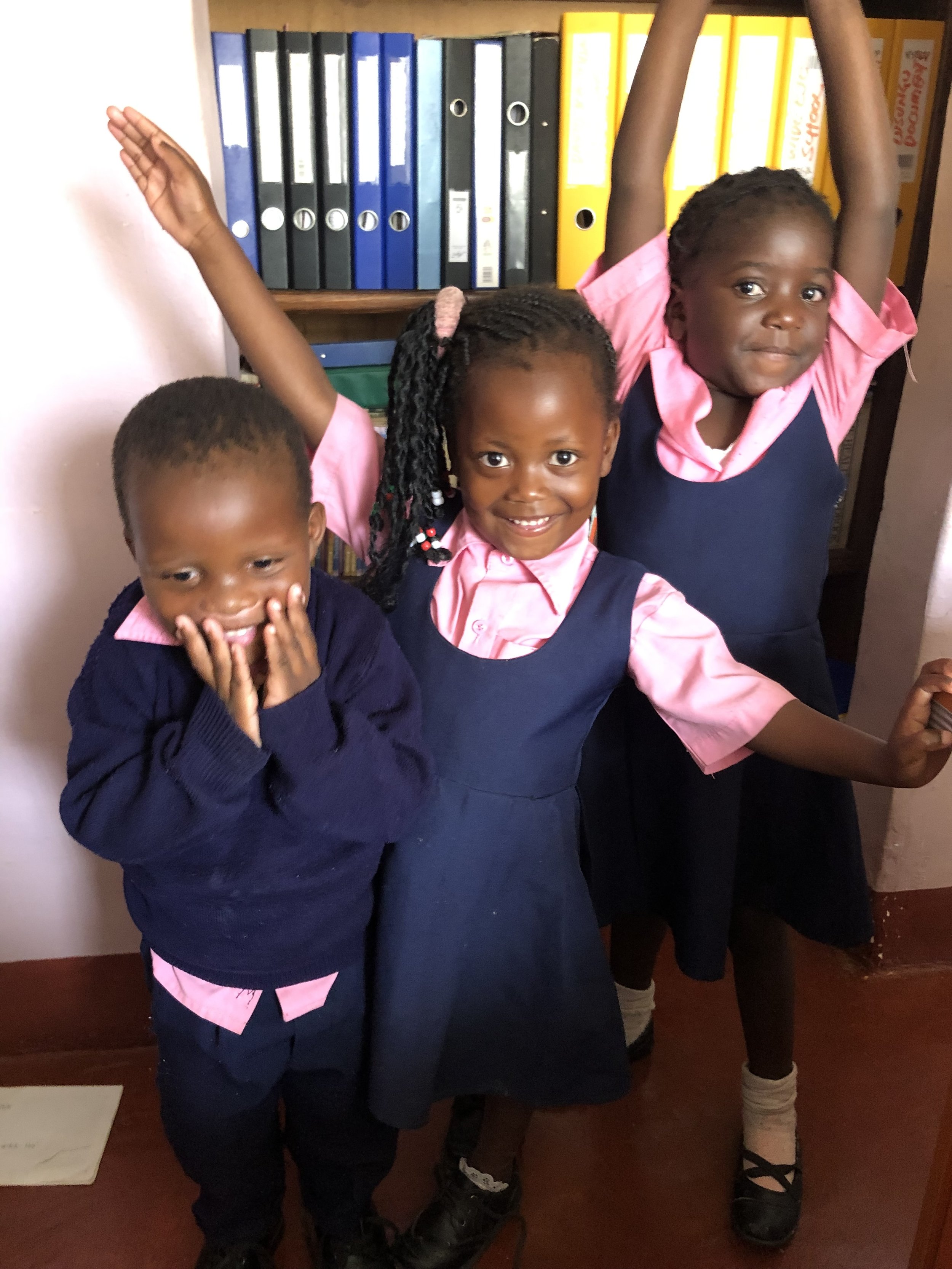 Three little kids in their school uniforms.