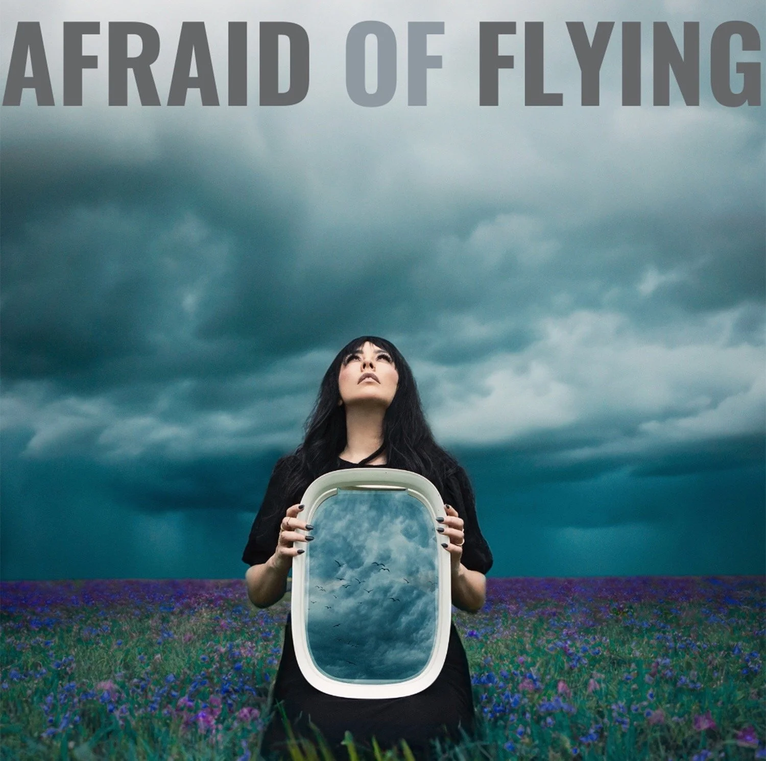 A woman with black hair holding a mirror reflecting cloudy skies with birds, standing in a purple flower field with dark storm clouds overhead, and text at the top reading 'AFAID OF FLYING'.