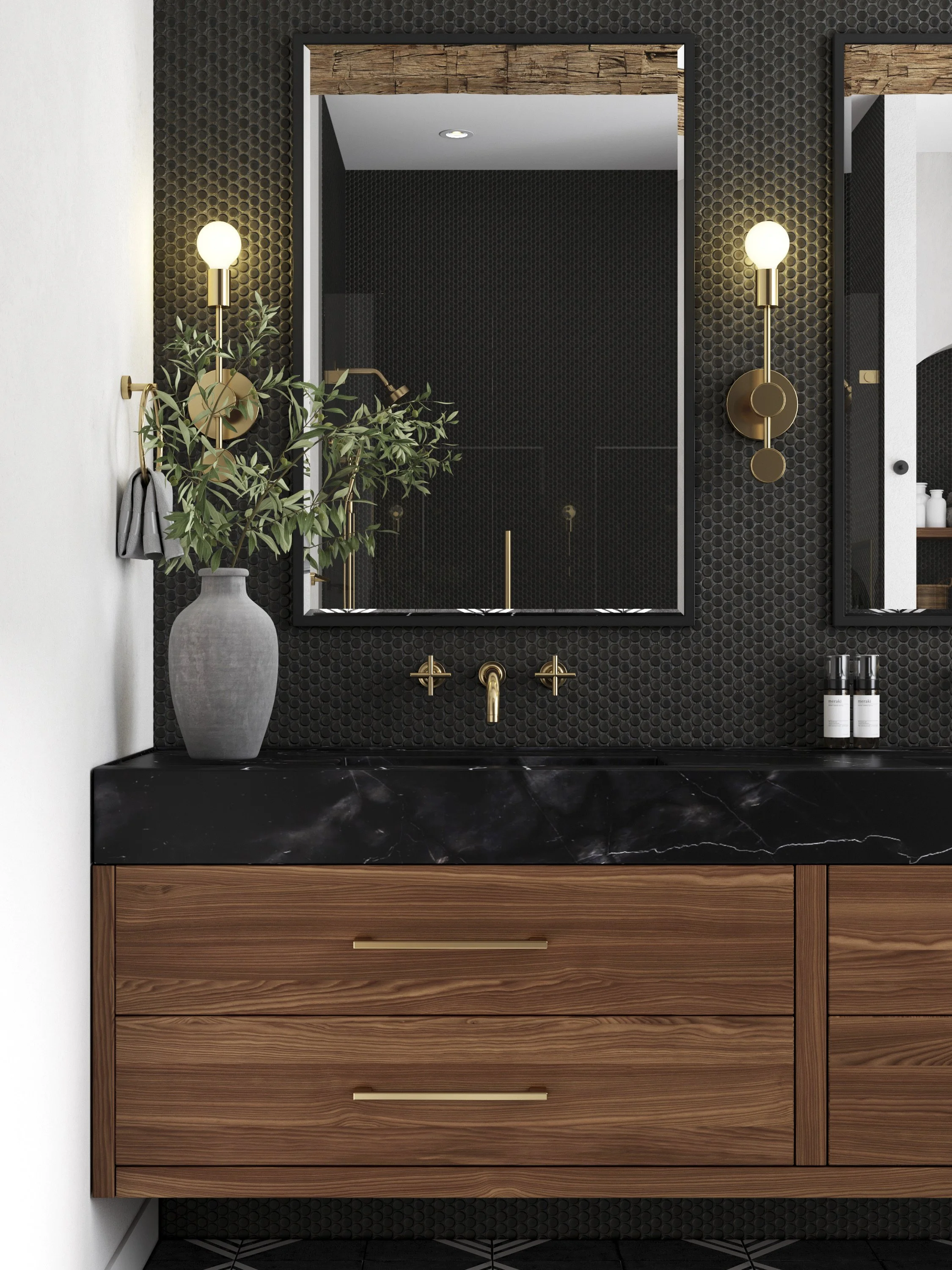 A modern bathroom vanity with a black marble countertop, wooden drawers with gold handles, and a large mirror. Two gold wall sconces illuminate the space, and a vase with green foliage sits on the left side of the countertop.
