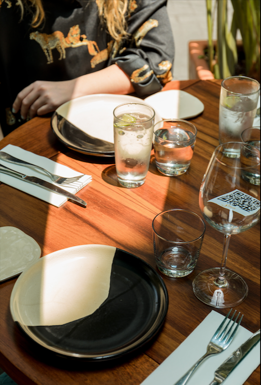 Mesa de comedor con platos, vasos con agua y hielo, y cubertería, en un ambiente de restaurante.