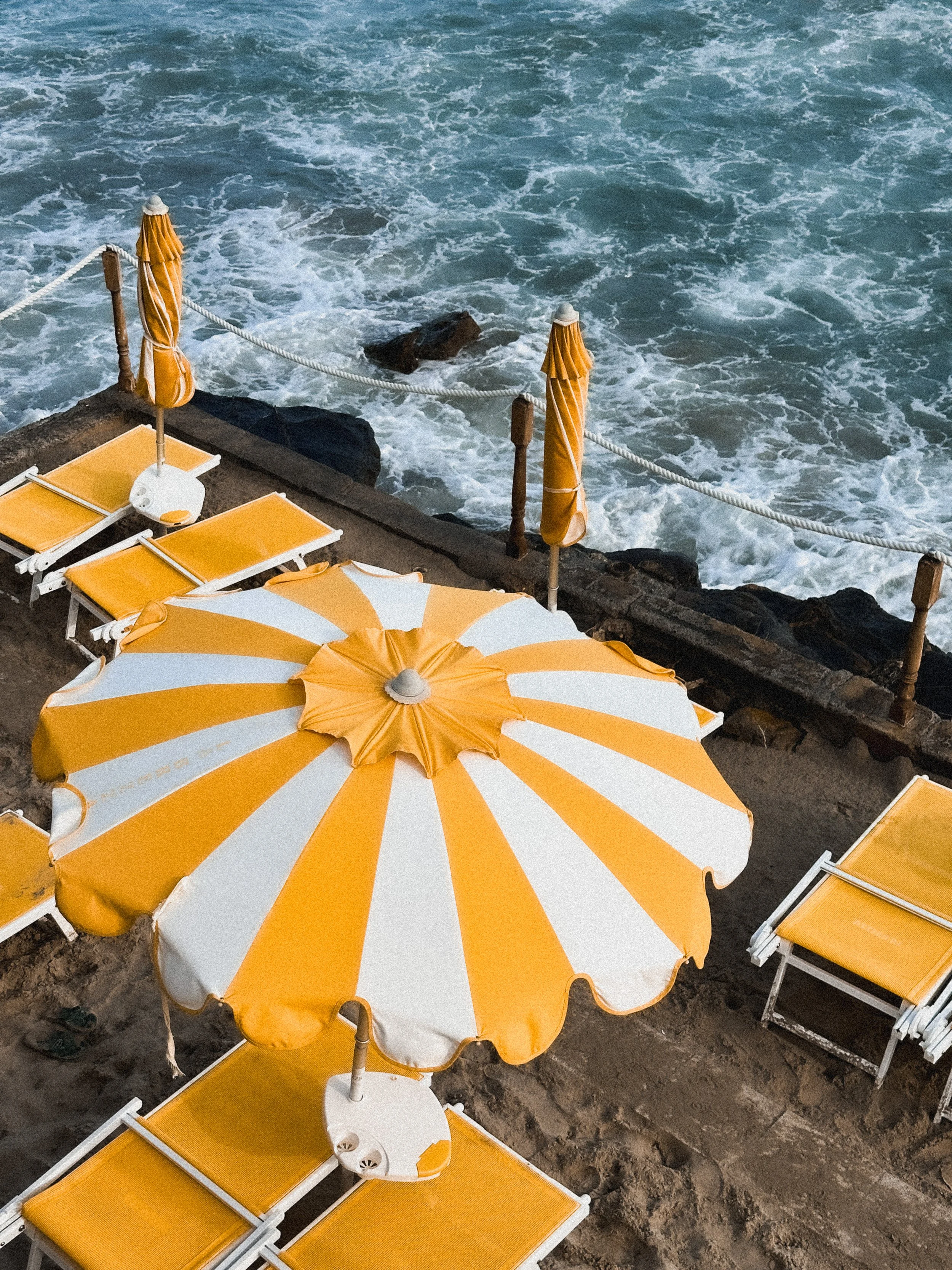 Yellow and white beach chairs and umbrellas with the ocean in the background.