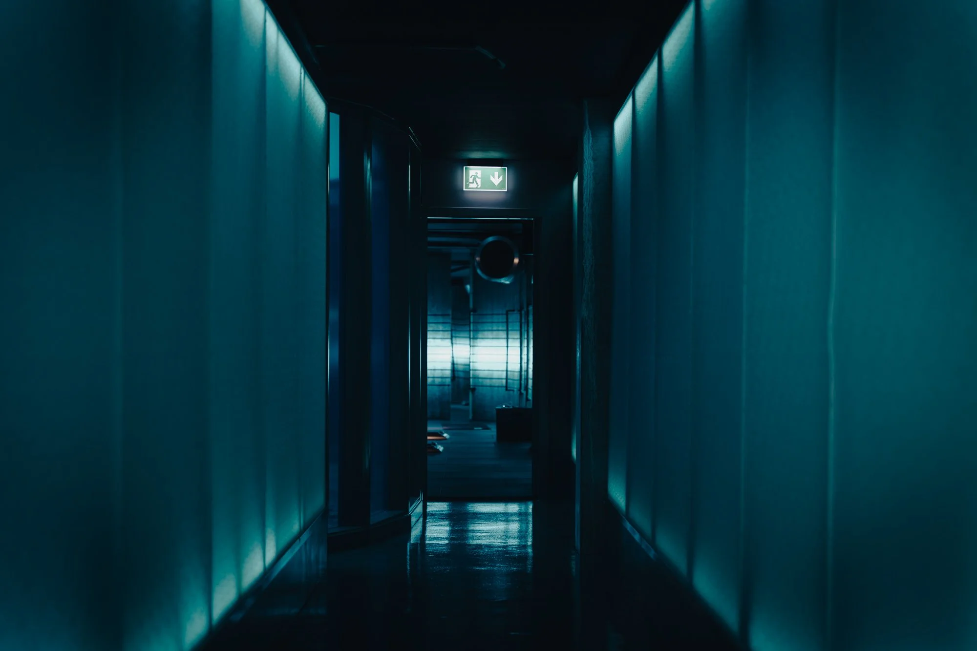 A dark hallway with blue lighting leading to a fitness studio.