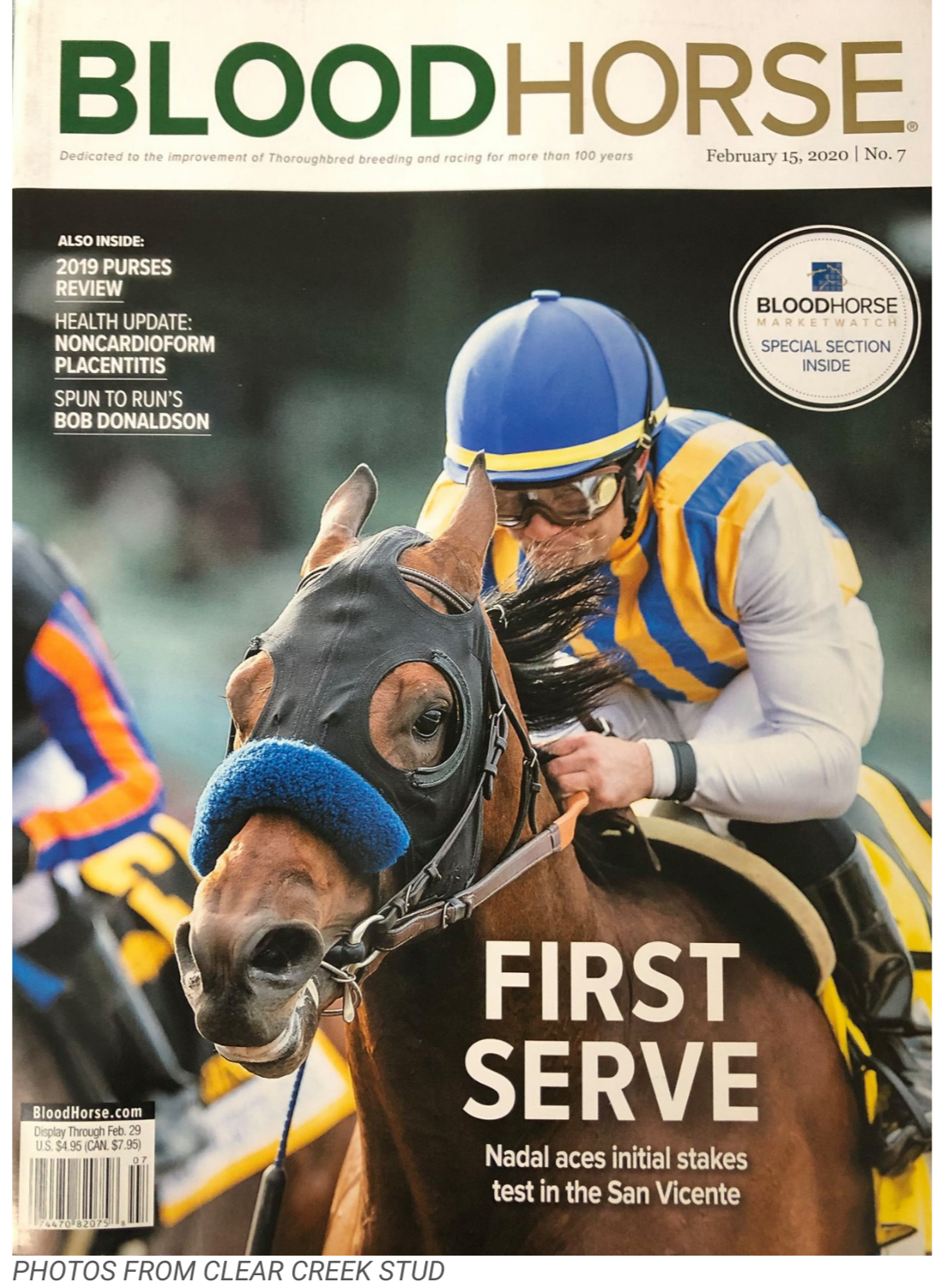 A jockey wearing a blue helmet and yellow-and-blue striped racing silks riding a horse with a black protective mask and blue noseband during a horse race. The magazine cover features the headline, 'First Serve,' about Rafael Nadal's initial stakes test at the San Vicente race.