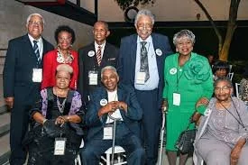 A group of eight diverse adults, some seated and some standing, smiling at a formal event.