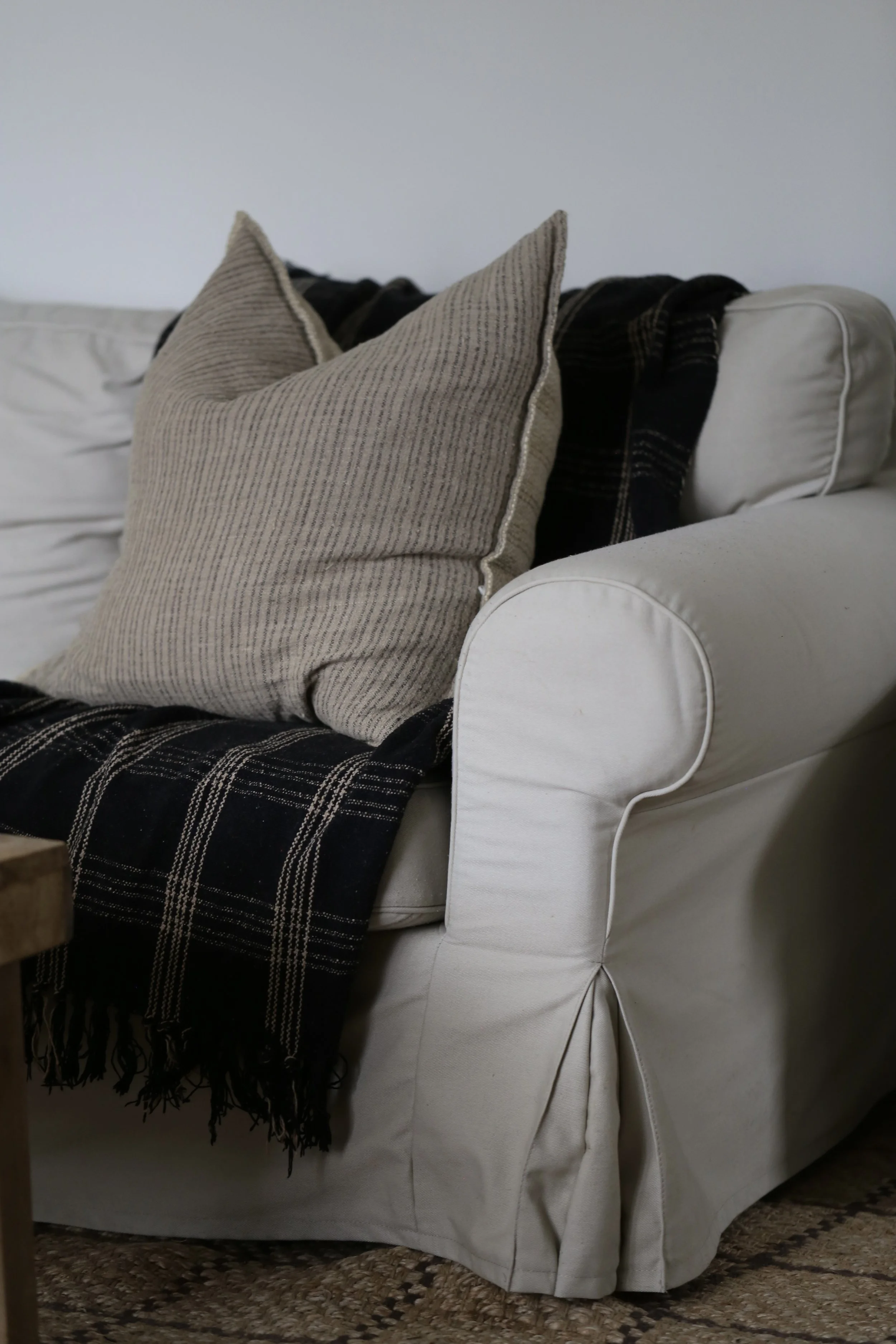 Cream sectional with black plaid blanket and pinstripe pillow
