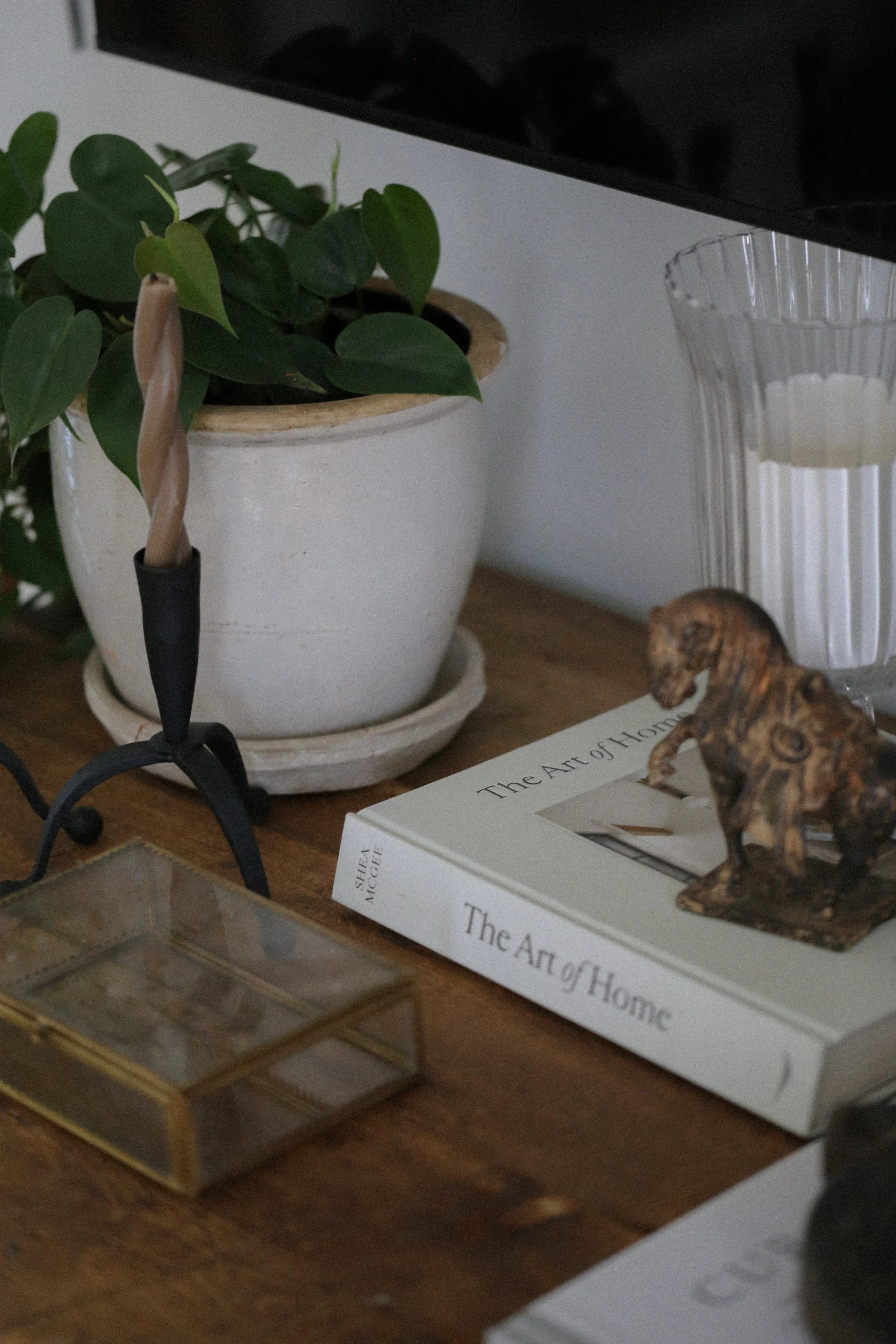 table display featuring books, candlesticks, horse figurine, and planted pot. cottage core interior design